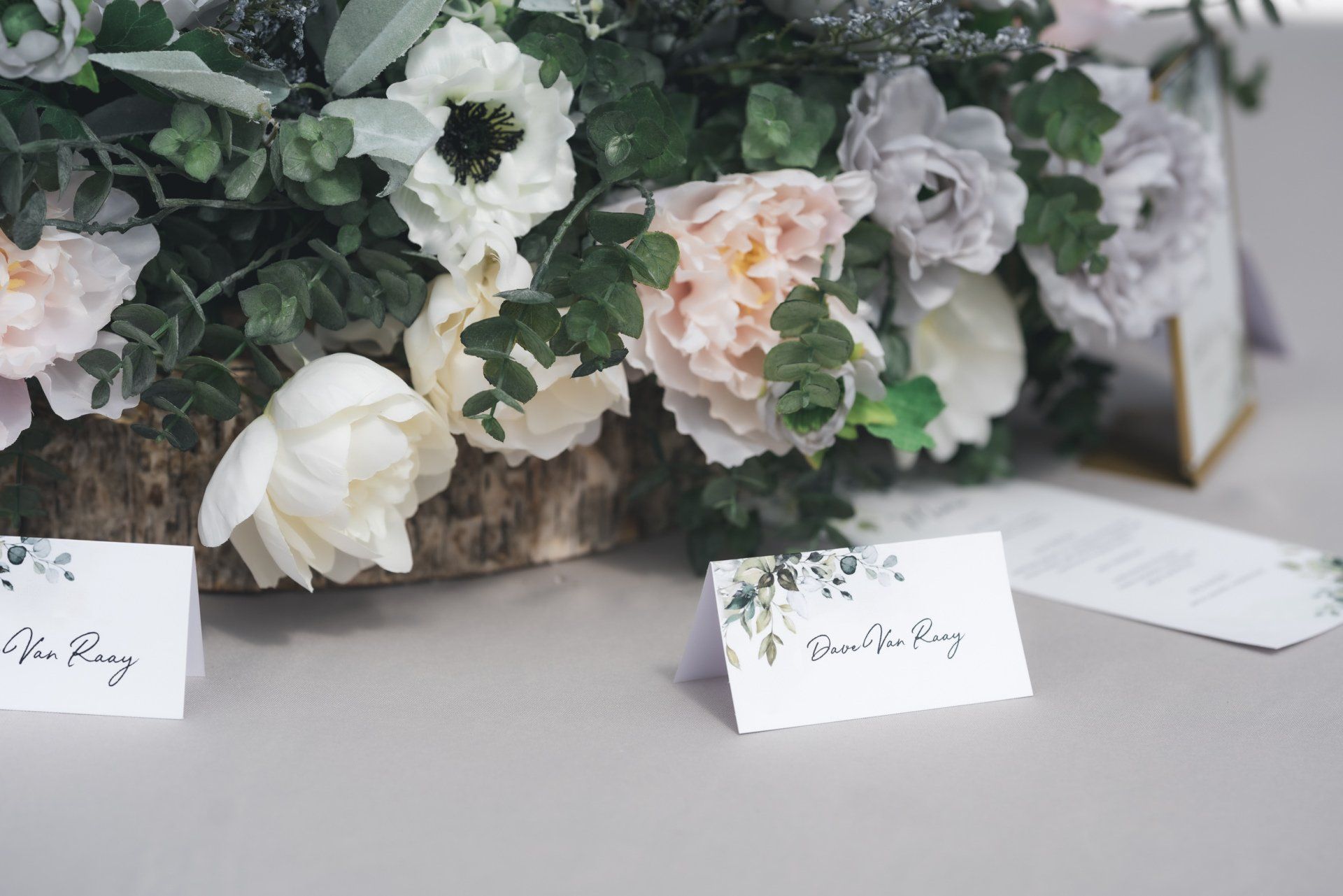 A table with flowers and place cards on it.