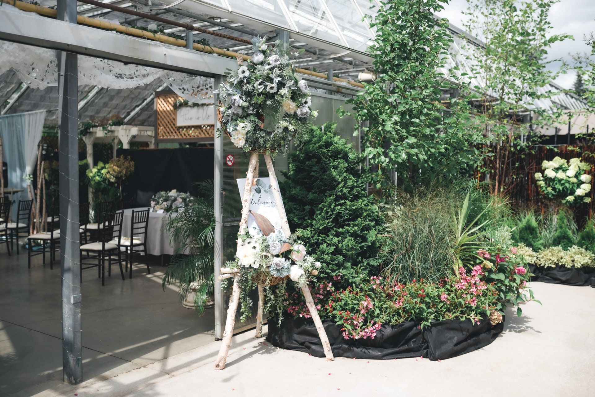 A greenhouse with a sign on an easel in the middle of it.
