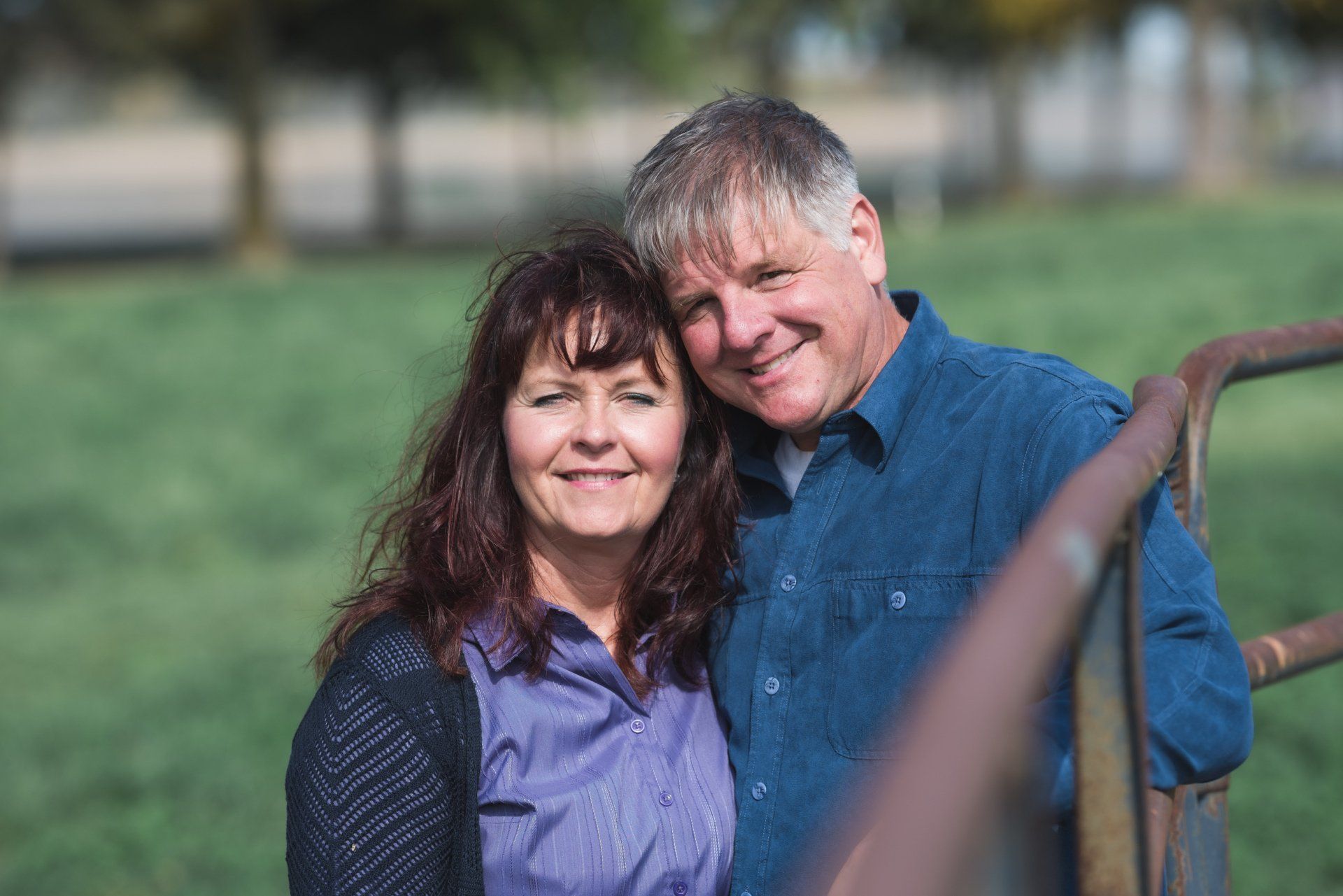 A man and a woman are posing for a picture in a field.