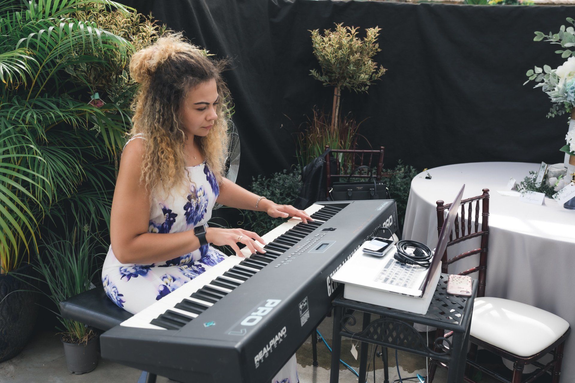 A woman is playing a keyboard in front of a table.
