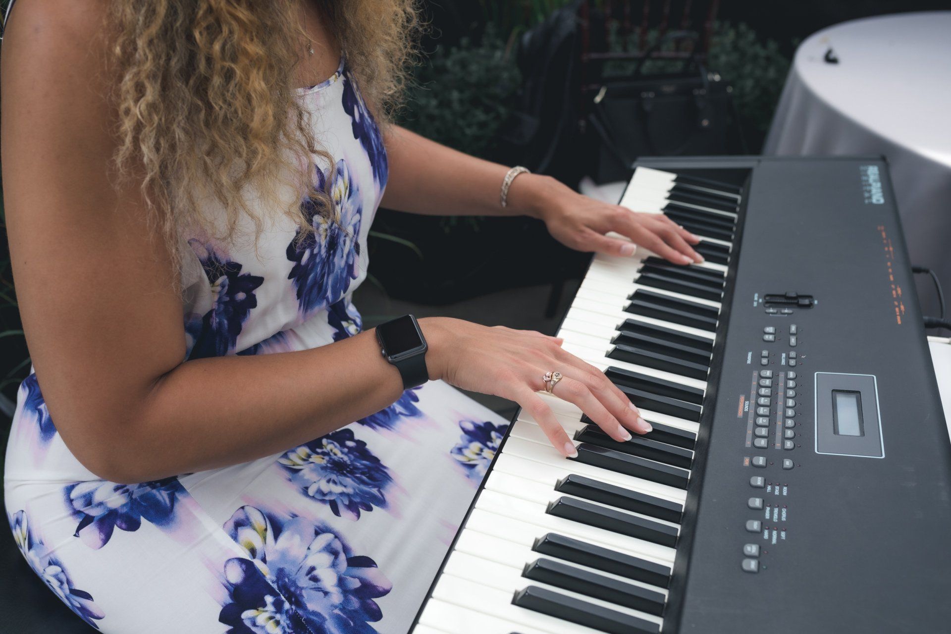 A woman in a floral dress is playing a keyboard.