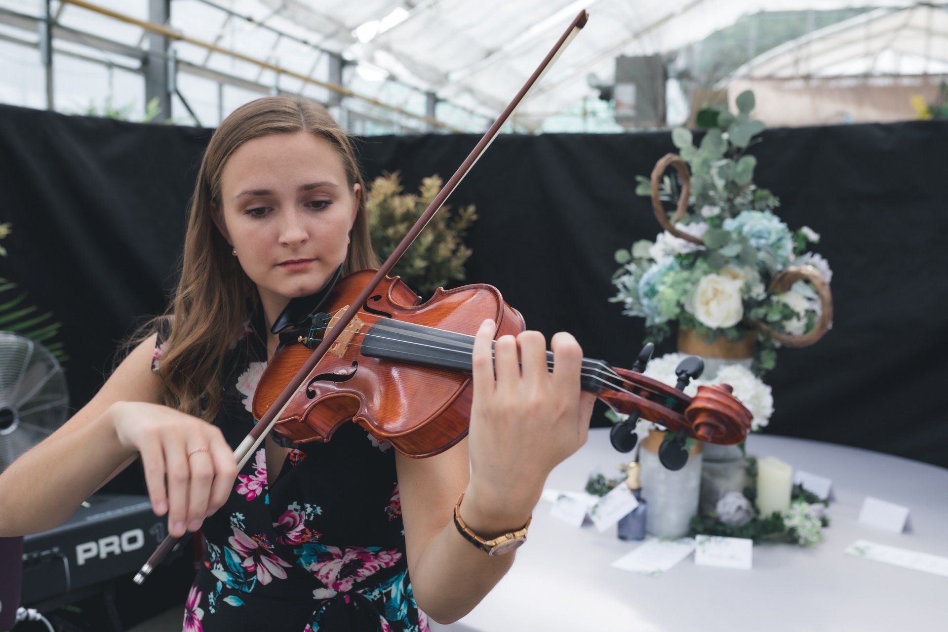 A woman is playing a violin in a greenhouse.