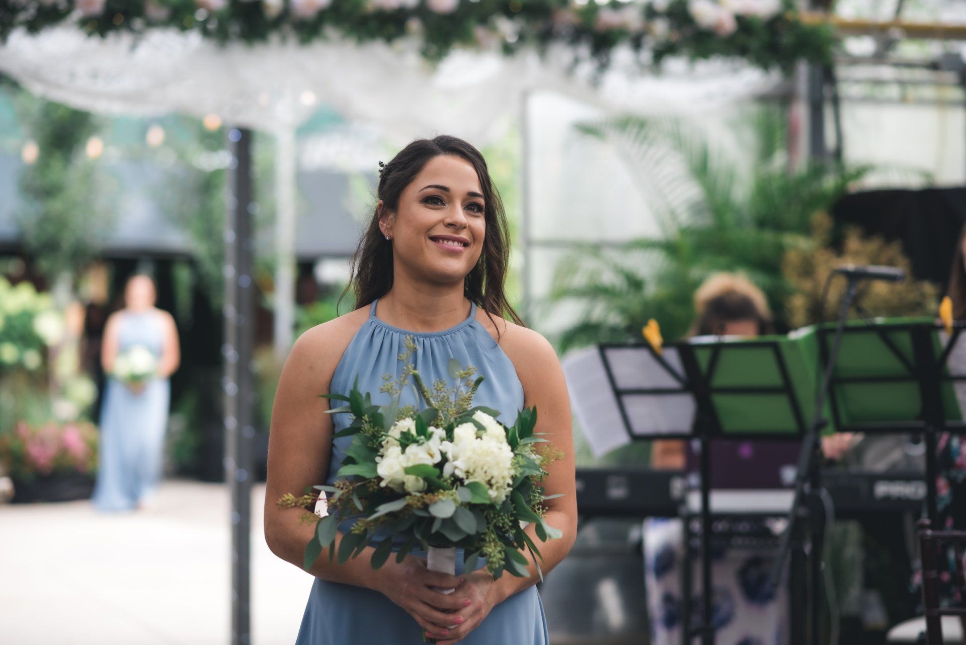 A woman in a blue dress is holding a bouquet of flowers and smiling.