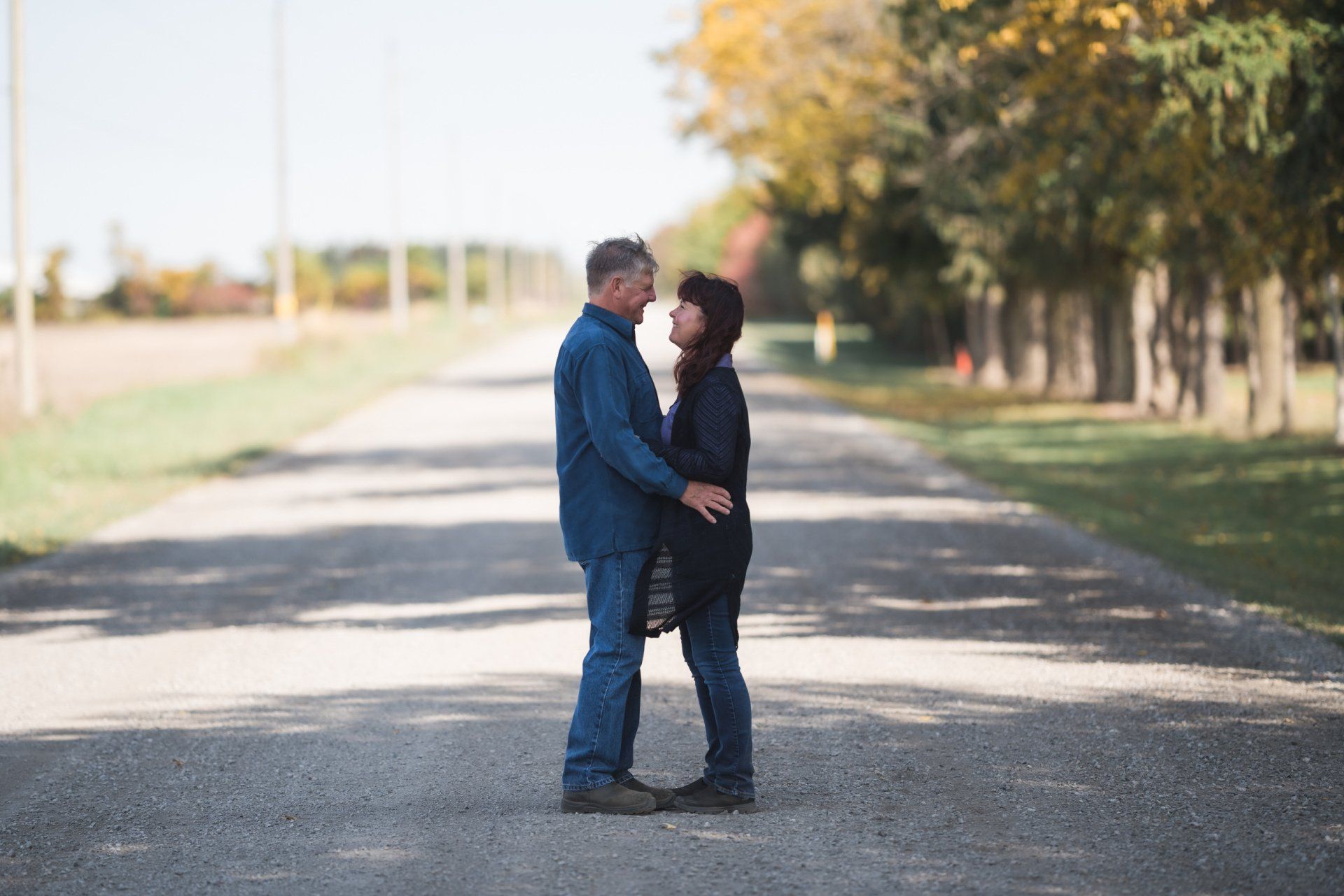 A man and a woman are standing next to each other on a dirt road.