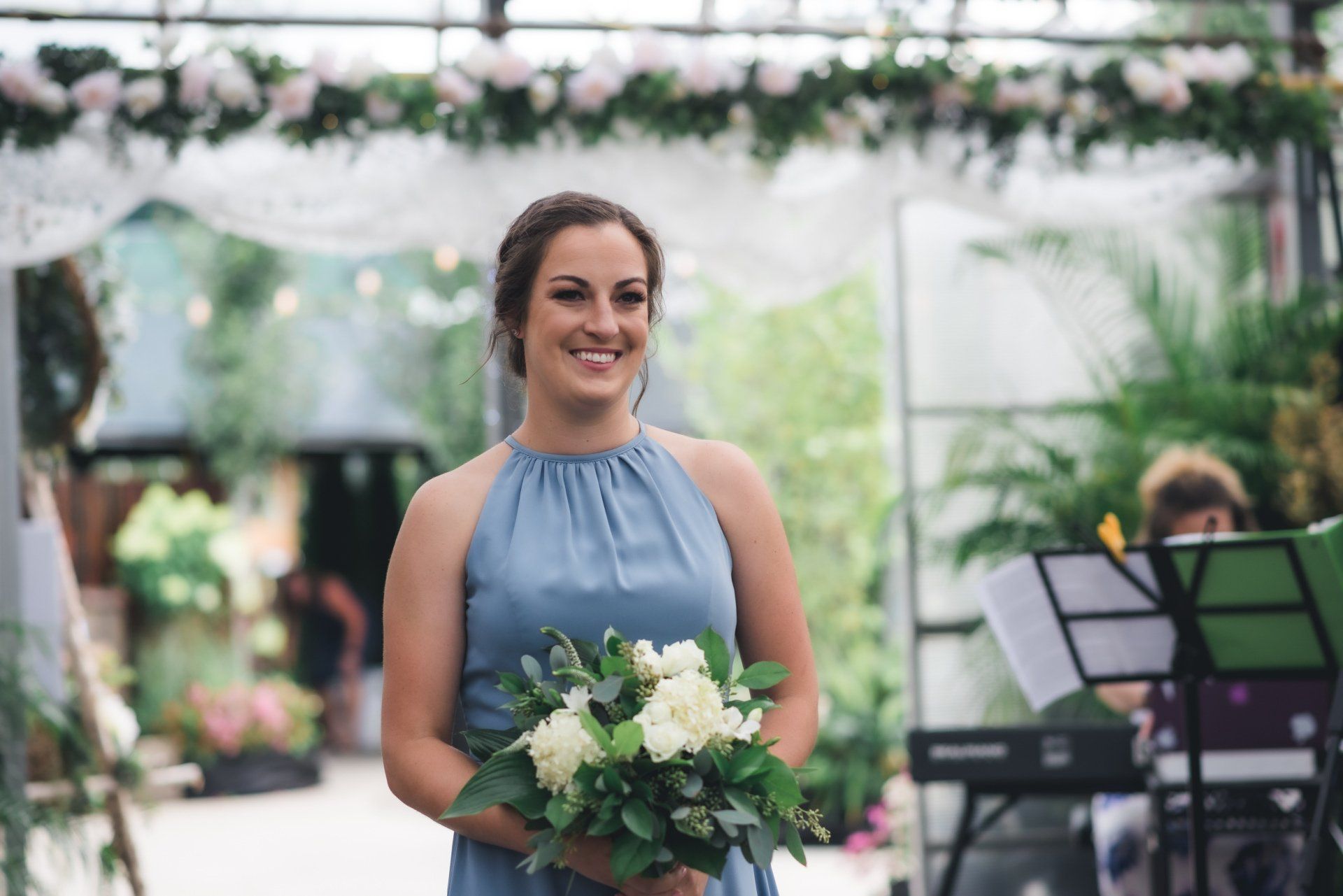 A woman in a blue dress is holding a bouquet of flowers and smiling.