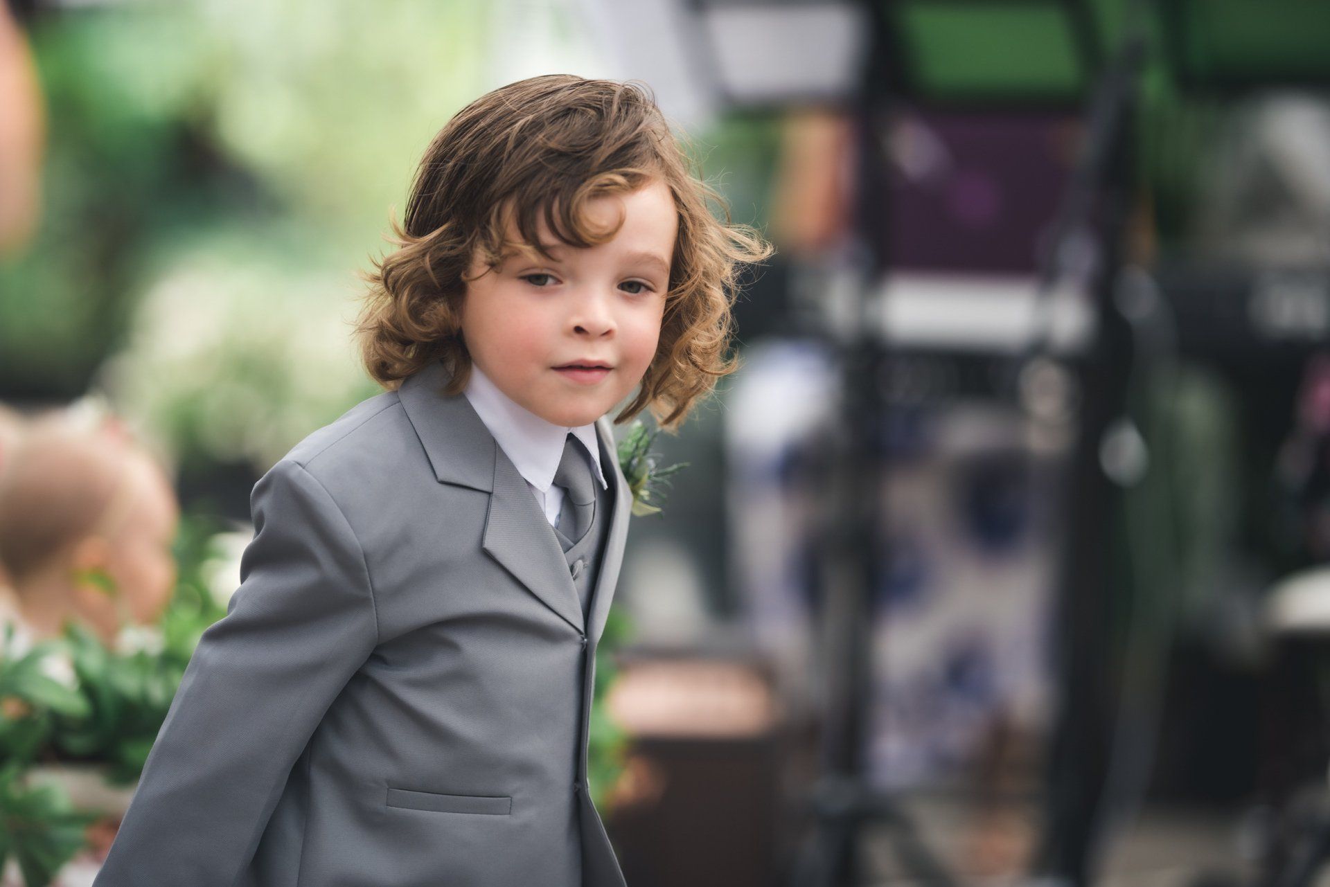 A young boy with curly hair is wearing a suit and tie.