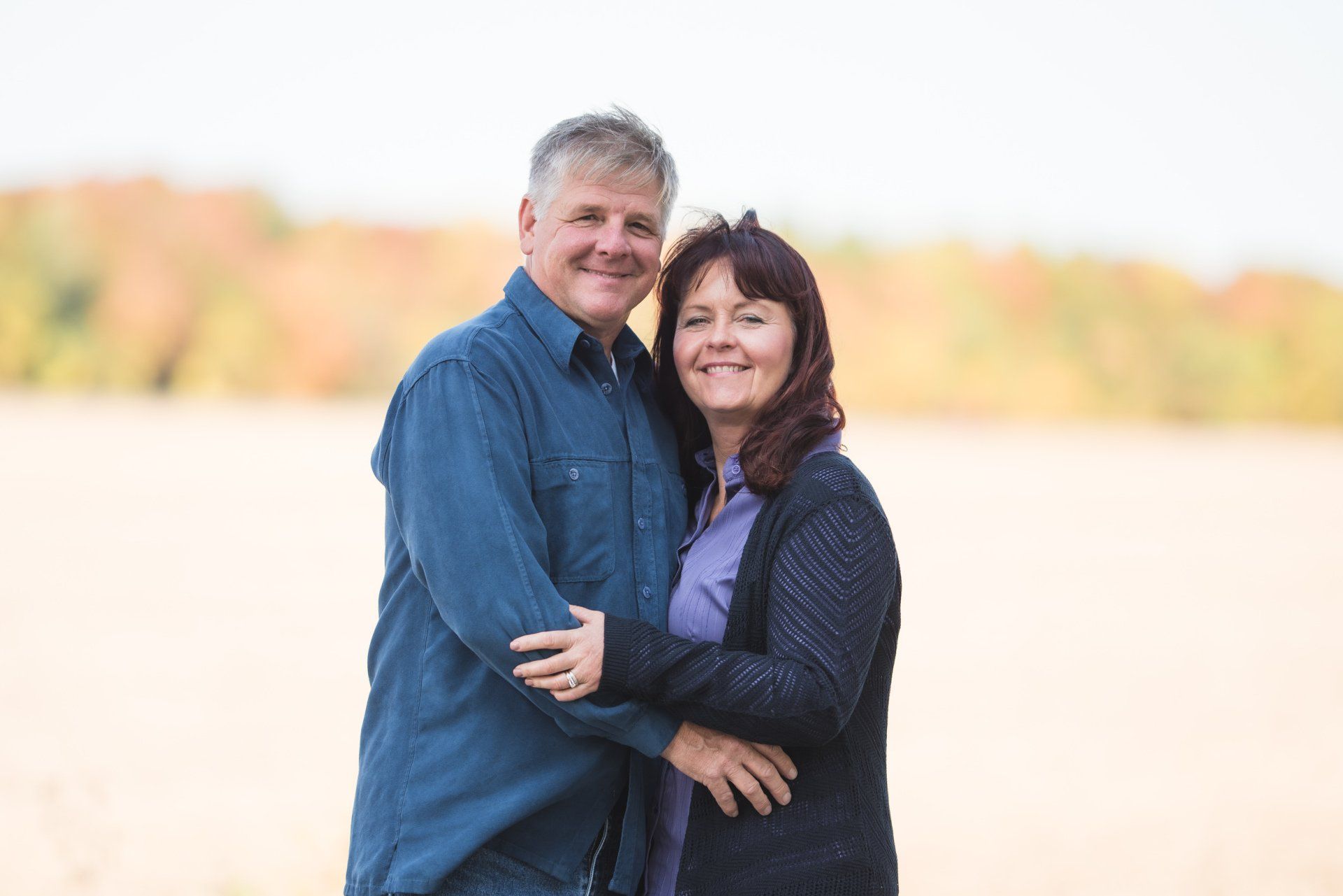 A man and a woman are hugging each other in a field.