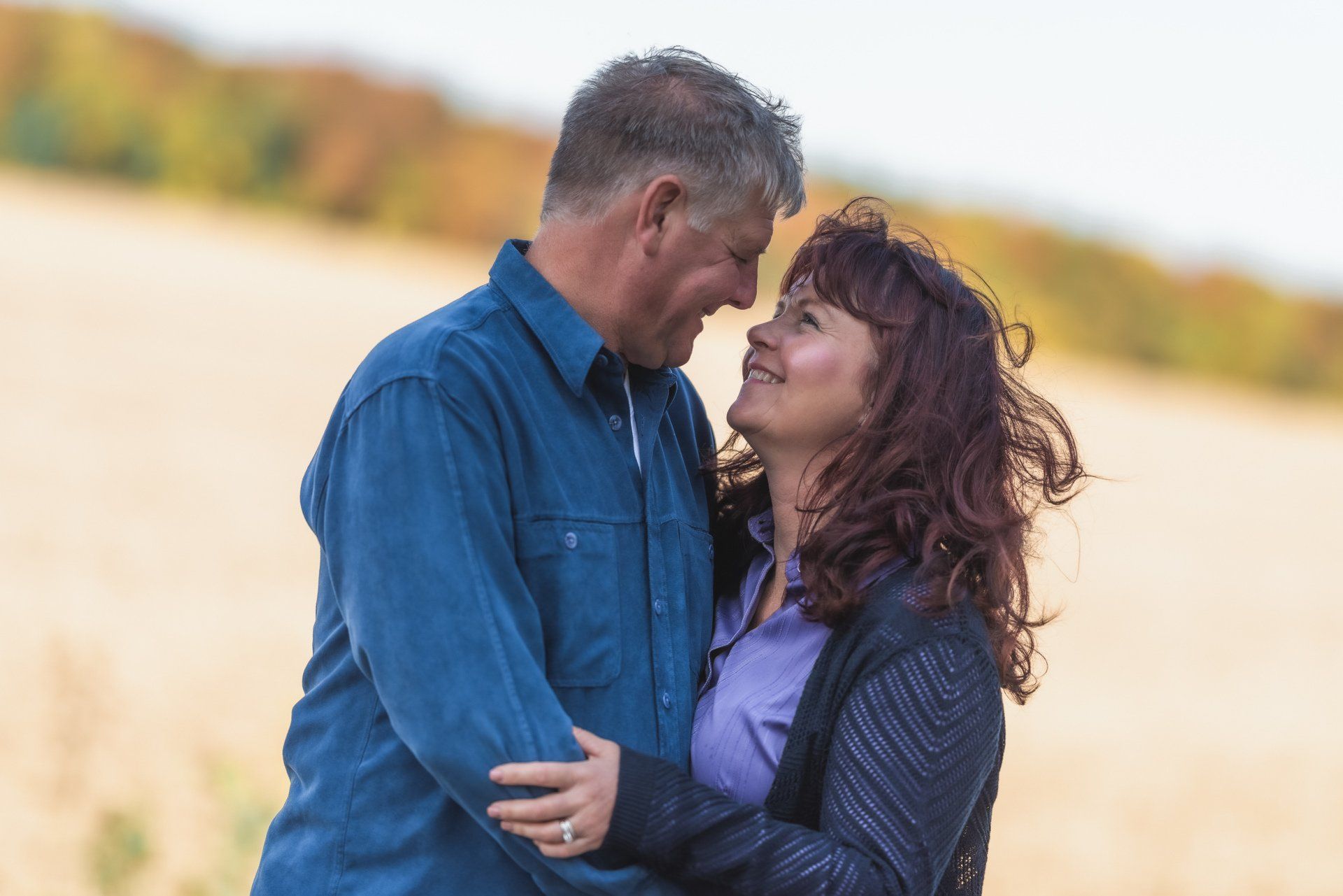 A man and a woman are hugging each other in a field.