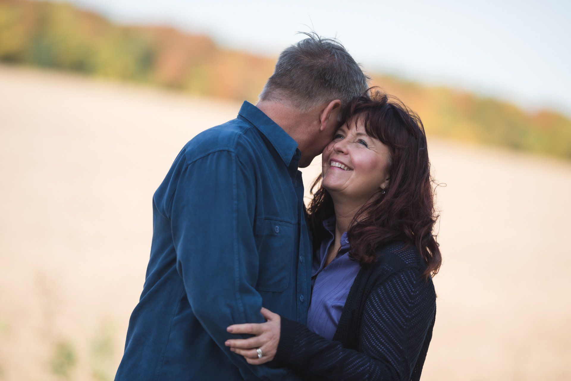 A man and a woman are hugging each other in a field.
