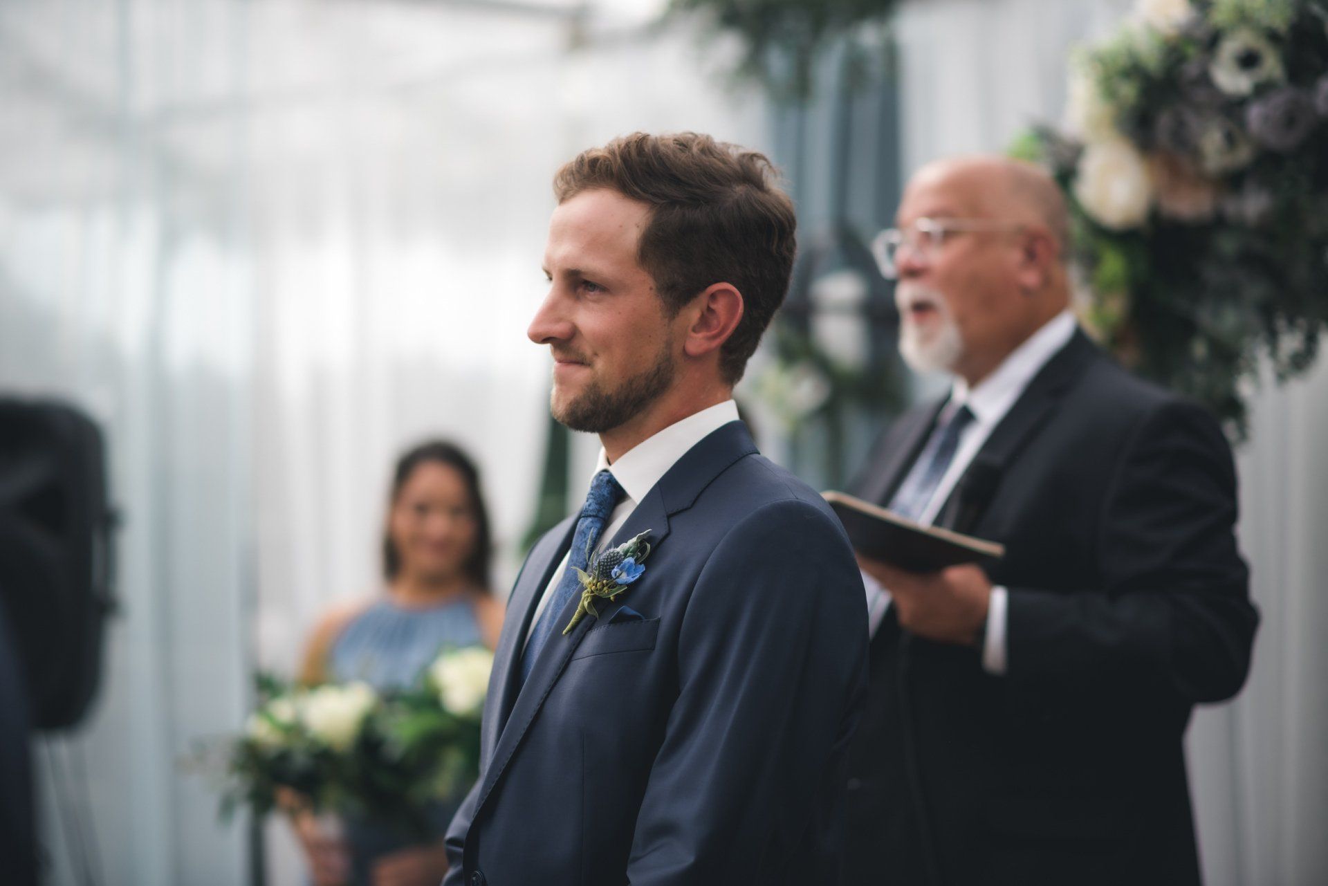A man in a suit and tie is waiting for his bride at a wedding ceremony.