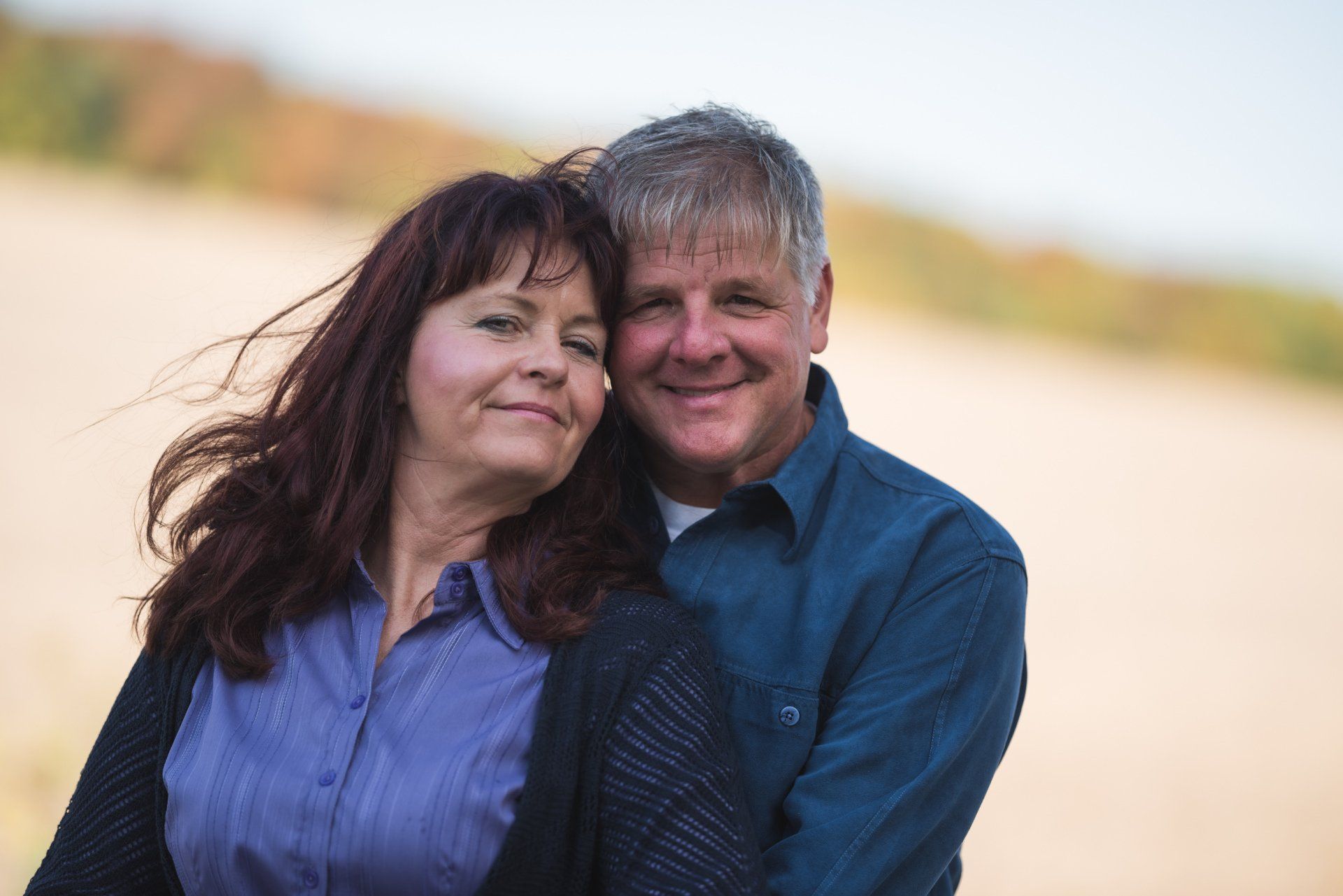 A man and a woman are hugging each other on a beach.