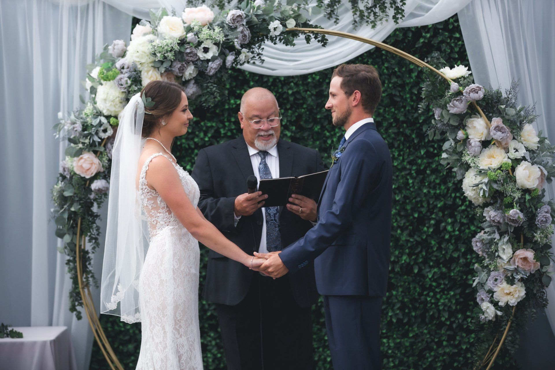 A bride and groom are holding hands during their wedding ceremony.