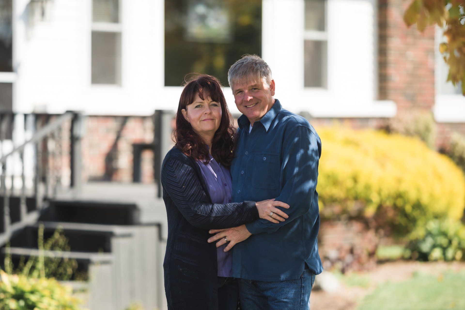 A man and a woman are standing in front of a house.