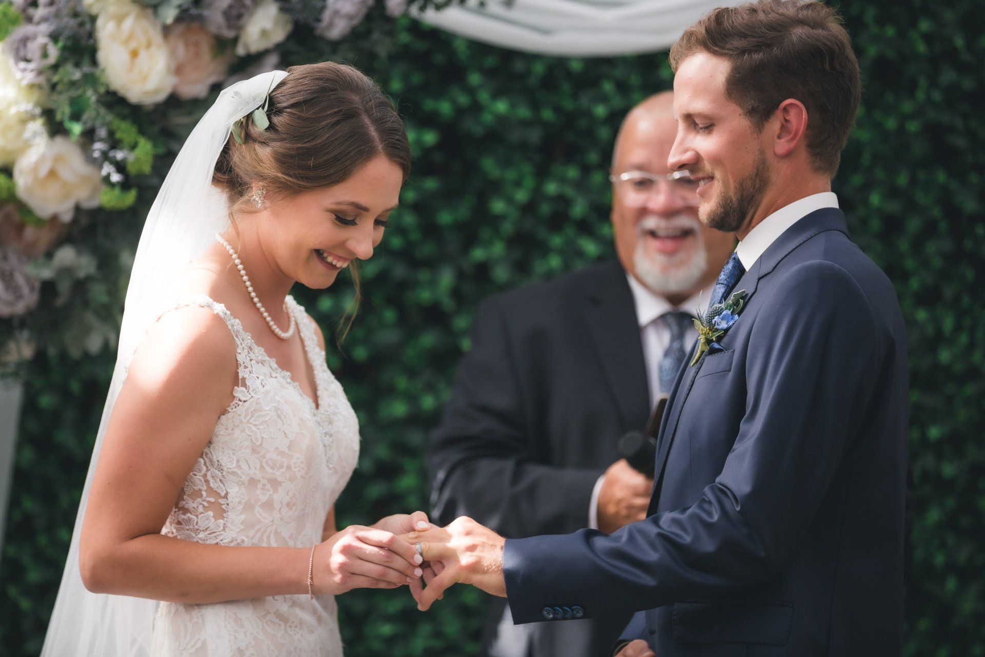 A bride and groom are getting married and the groom is putting the ring on the bride 's finger.