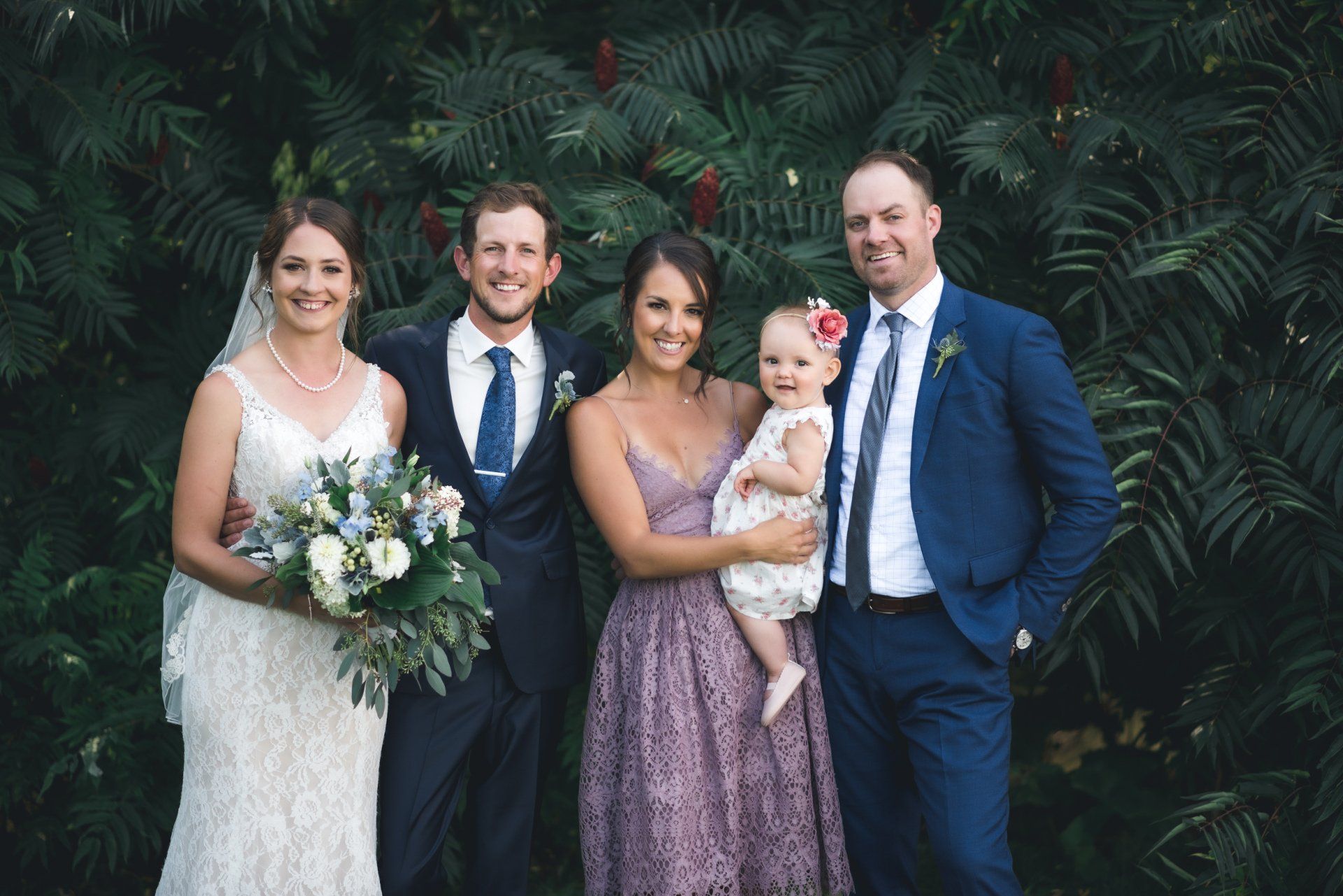 A bride and groom are posing for a picture with their wedding party.
