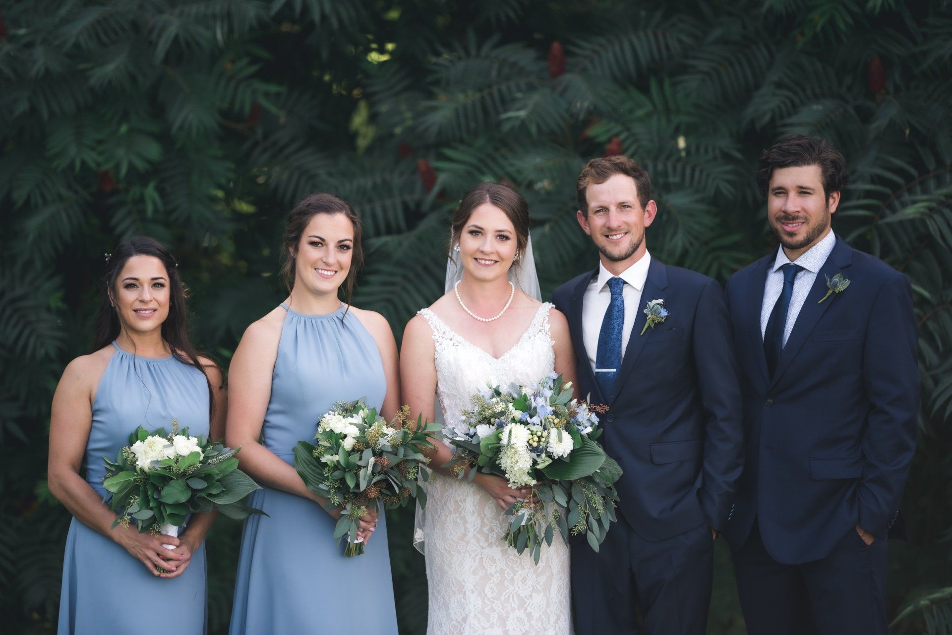 The bride and groom are posing for a picture with their wedding party.