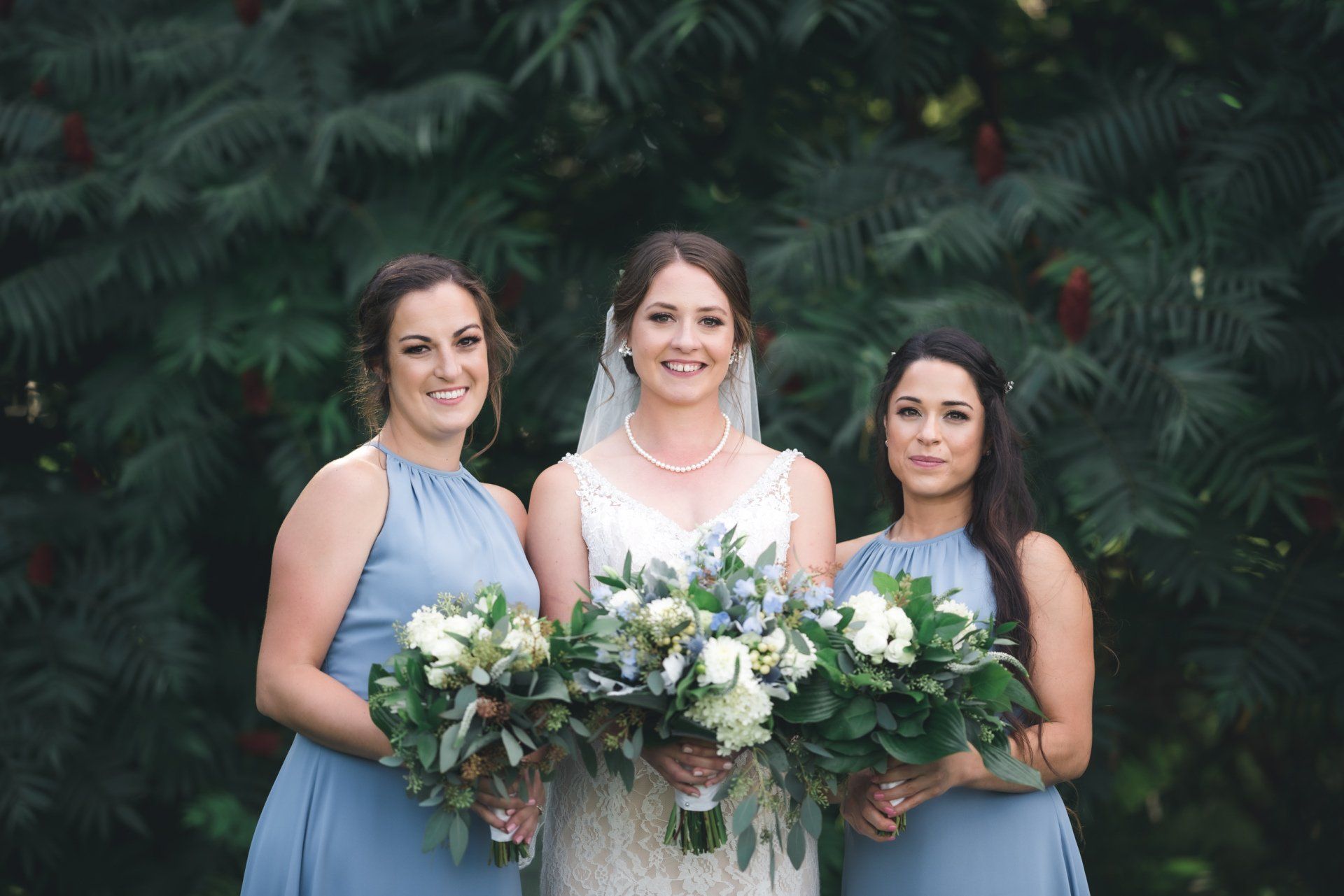 A bride and her bridesmaids are posing for a picture while holding bouquets of flowers.