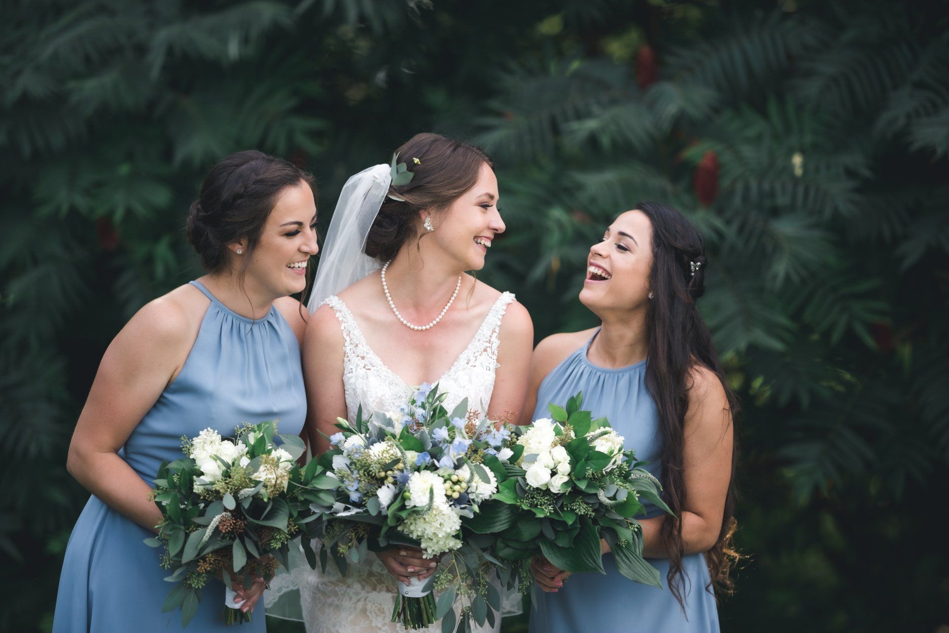A bride and her bridesmaids are standing next to each other holding bouquets of flowers.