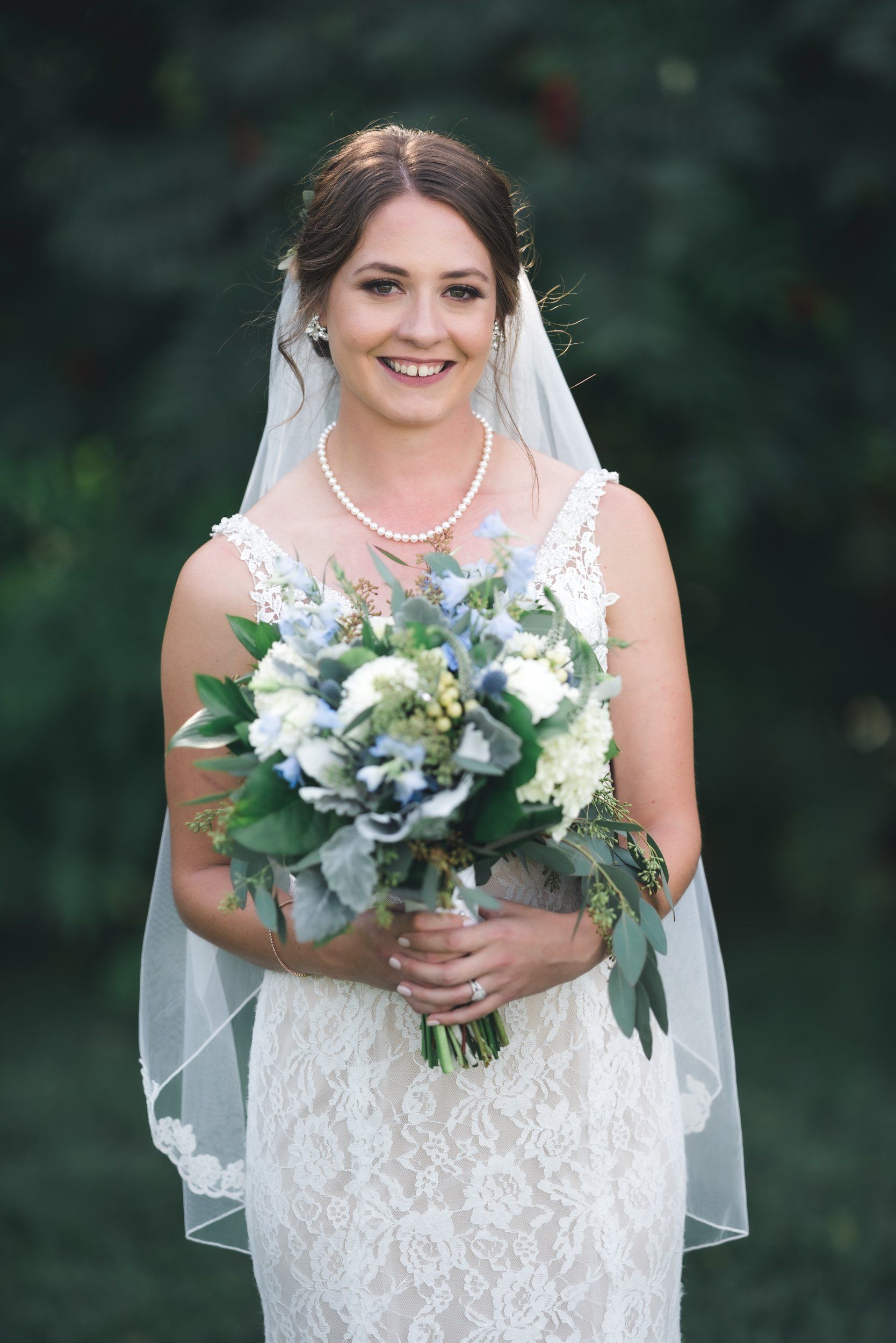 The bride is wearing a veil and holding a bouquet of flowers.