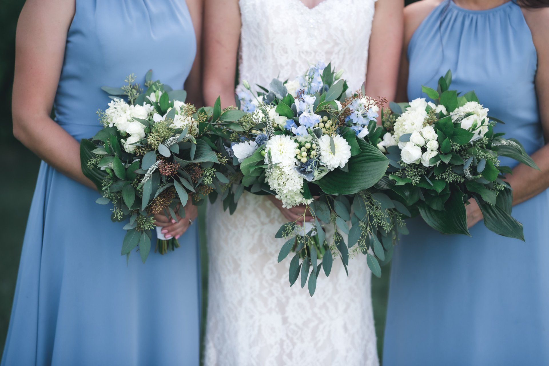 The bride and her bridesmaids are wearing light blue dresses and holding bouquets of flowers.