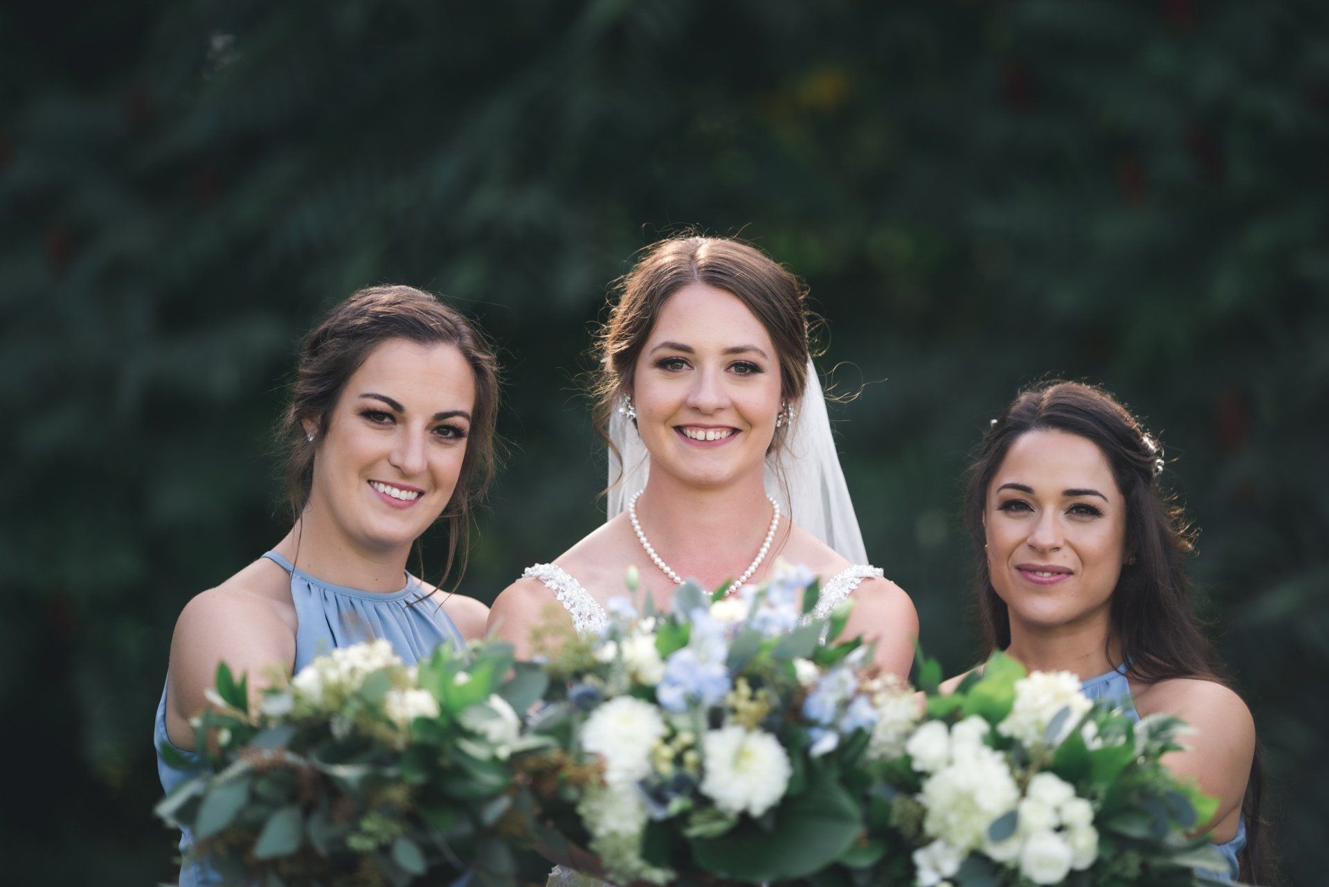 A bride and her bridesmaids are posing for a picture while holding bouquets of flowers.