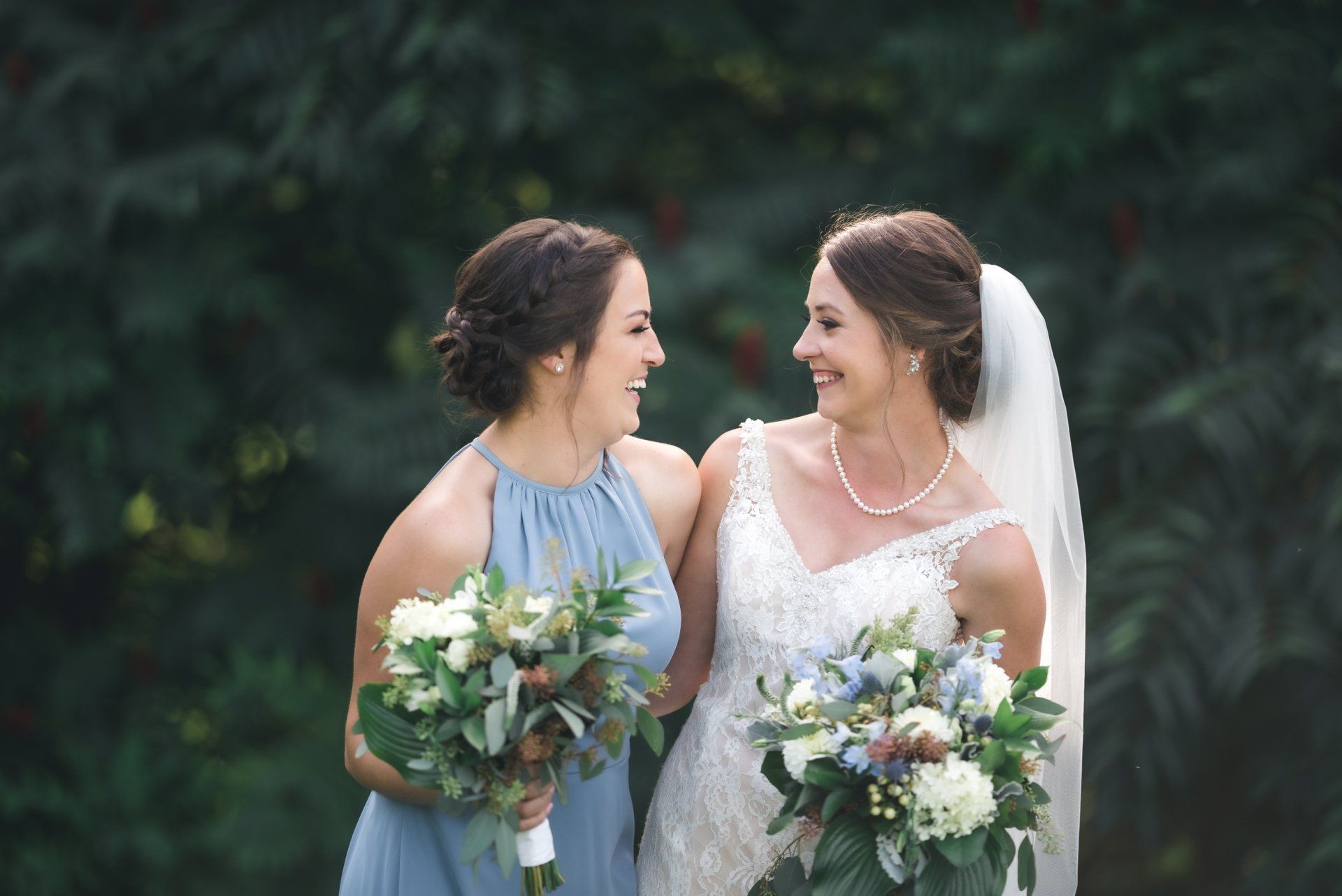 A bride and her bridesmaid are posing for a picture together.