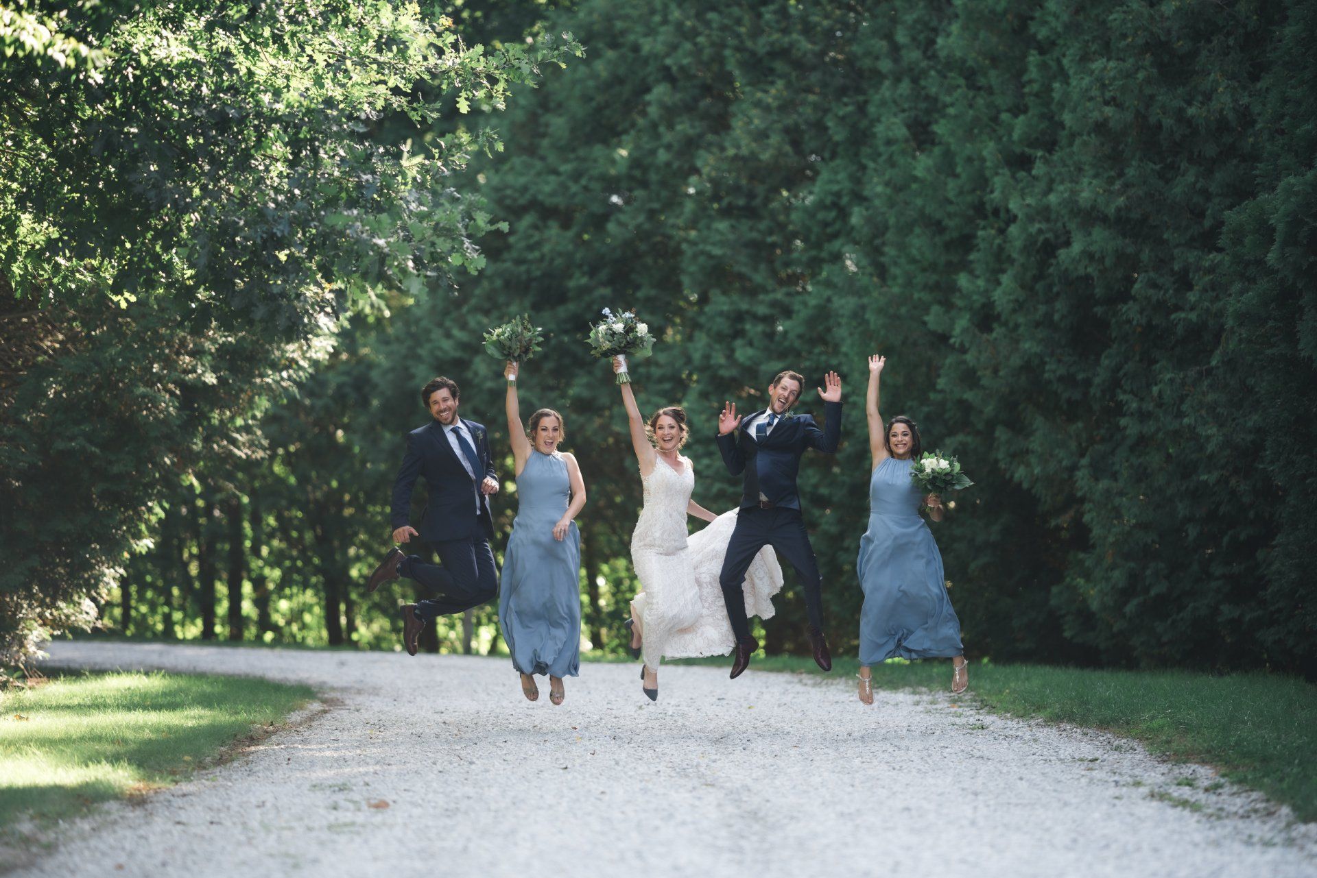 A bride and groom are jumping in the air with their bridesmaids.