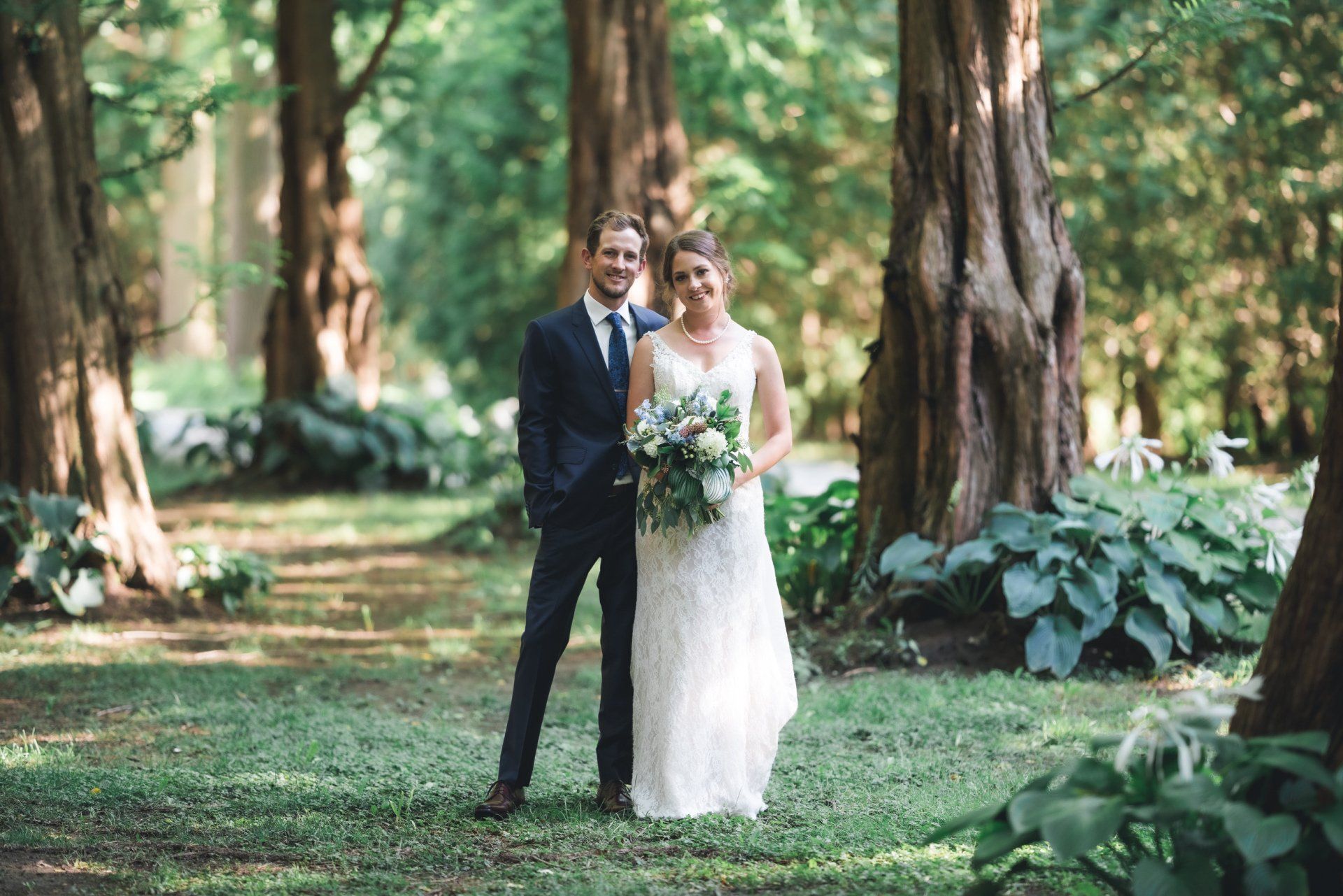 A bride and groom are posing for a picture in the woods.