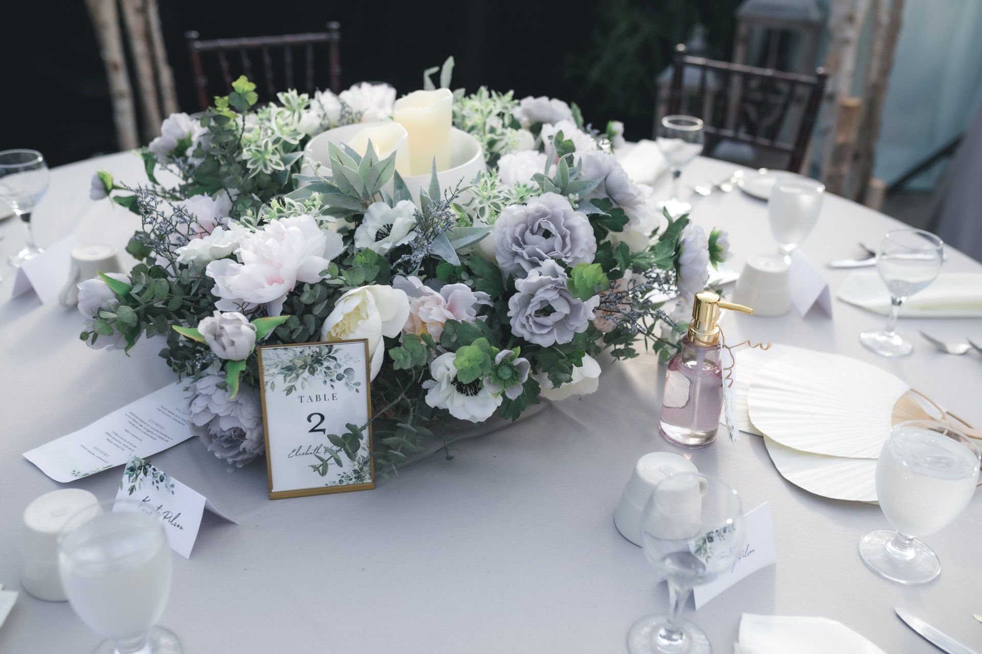 A table set for a wedding reception with a centerpiece of flowers and a table number.