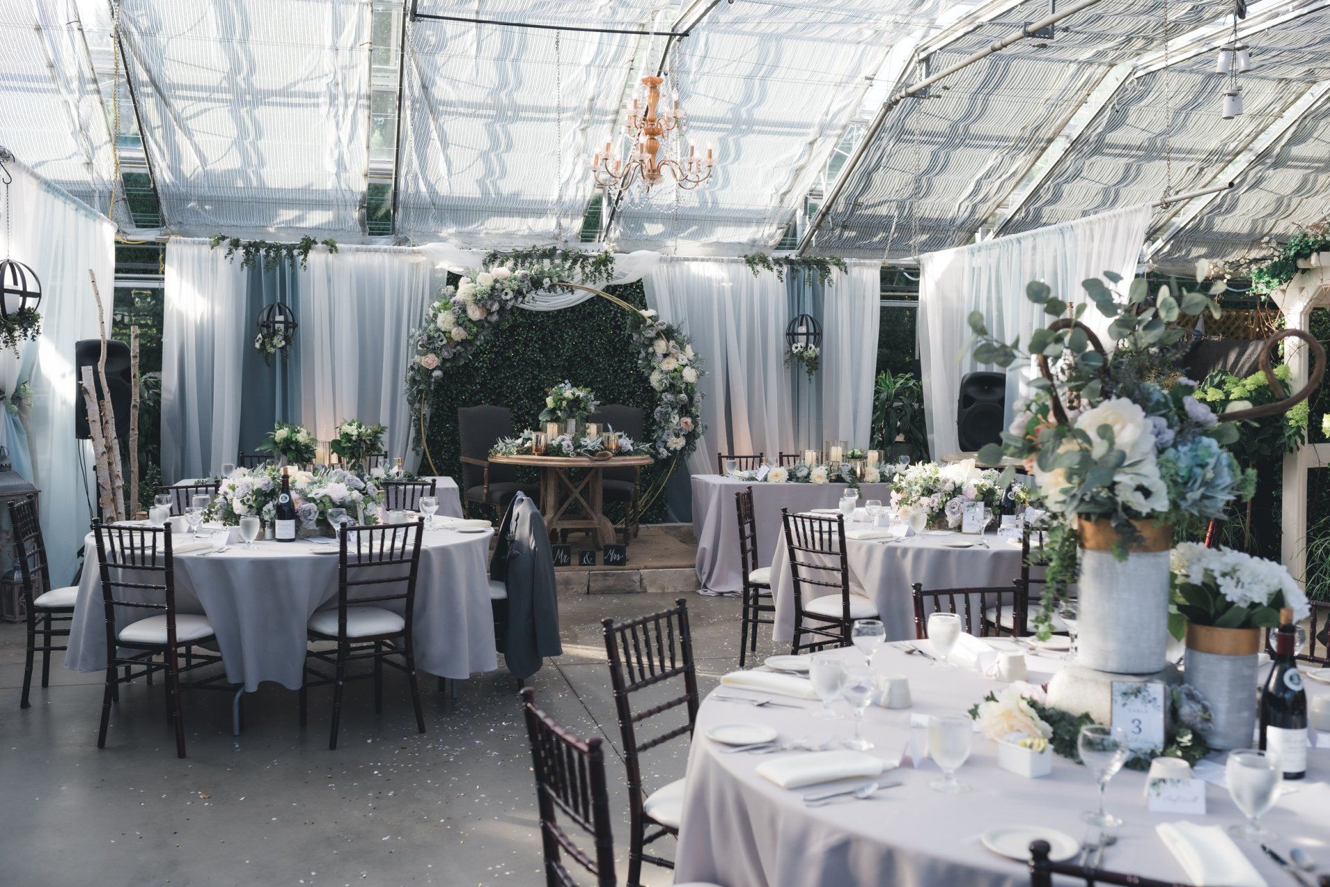 A greenhouse filled with tables and chairs set up for a wedding reception.