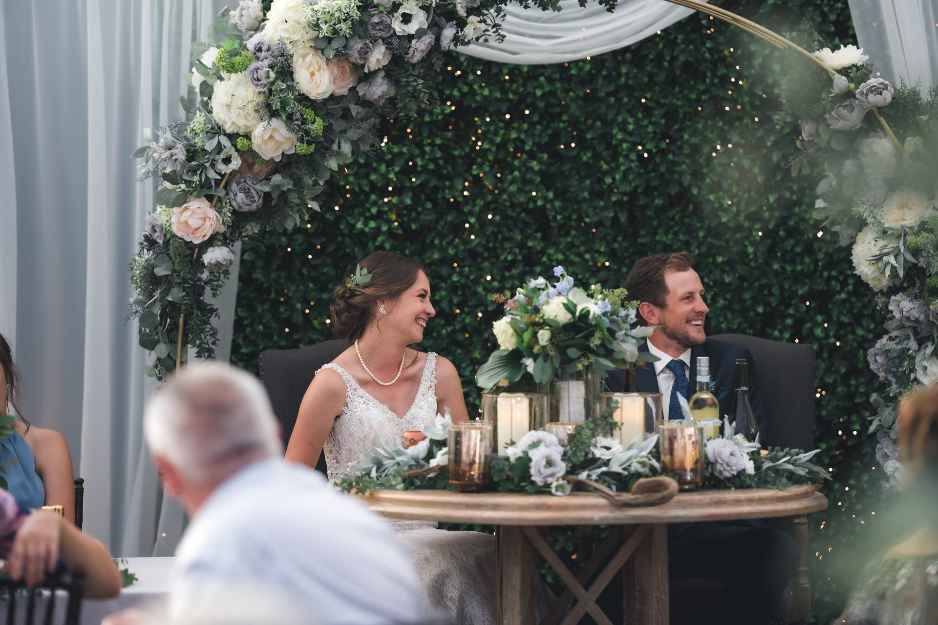 A bride and groom are sitting at a table at a wedding reception.