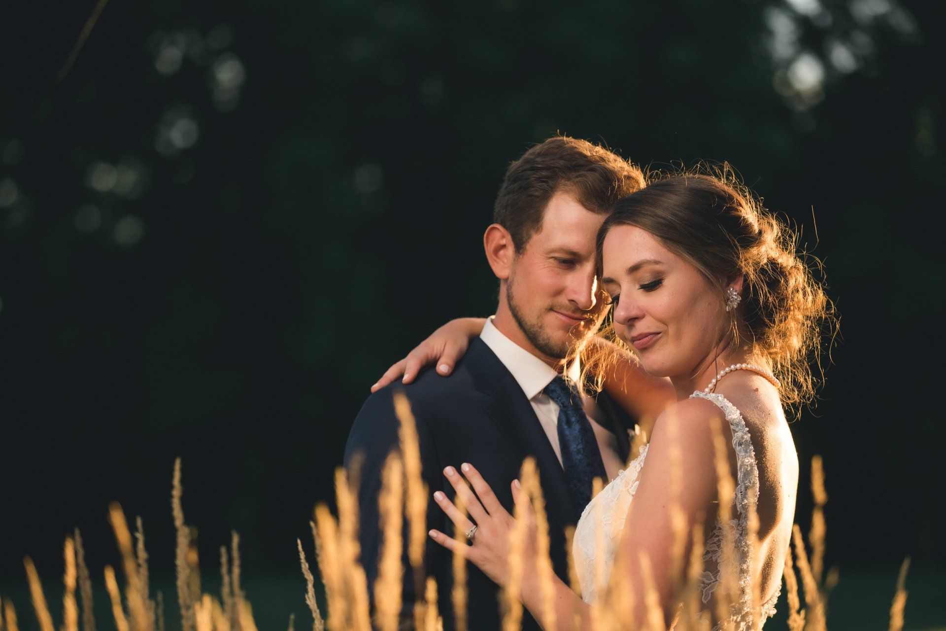 A bride and groom are posing for a picture in a field of tall grass.
