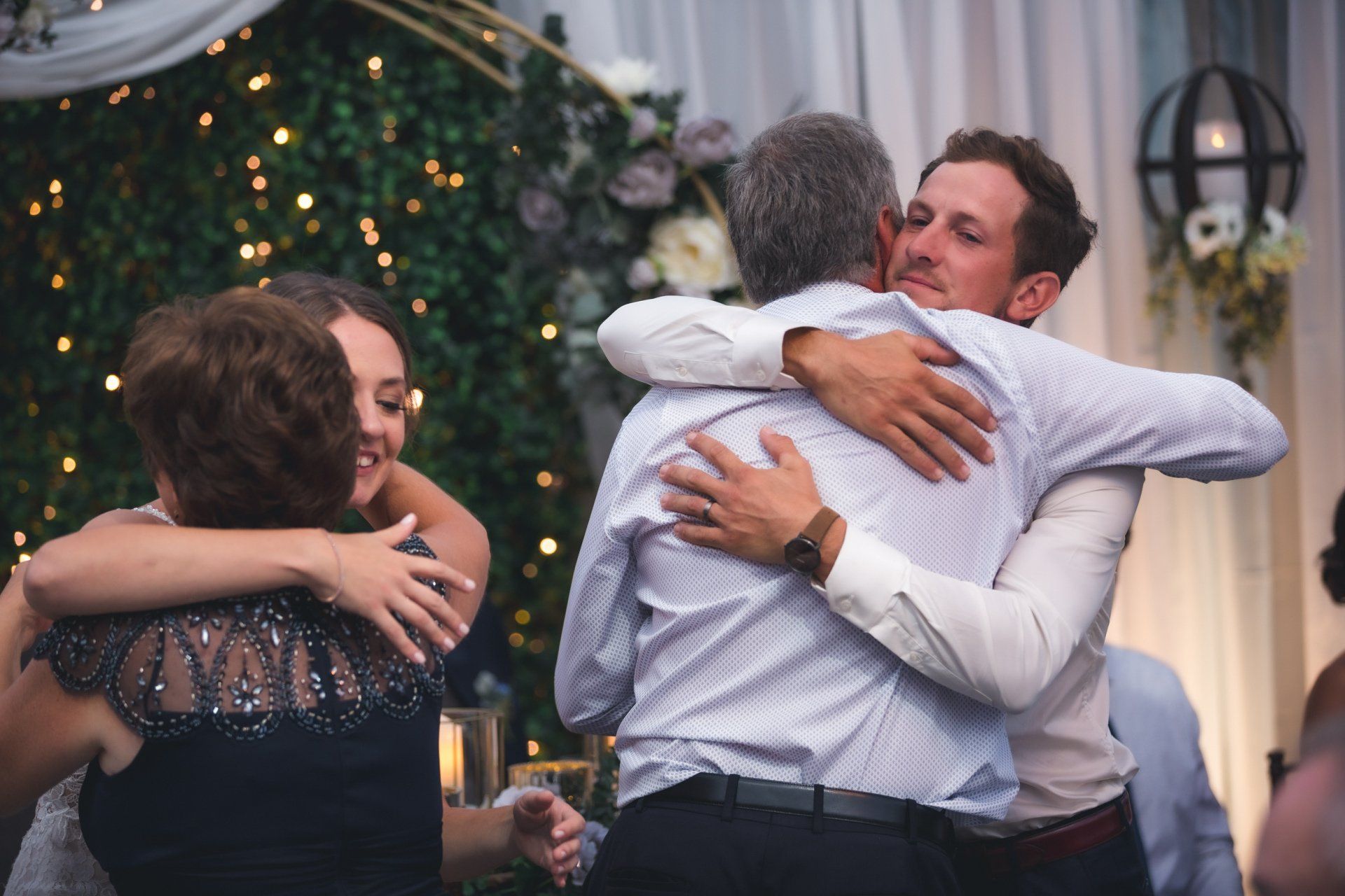 A group of people are hugging each other at a wedding reception.