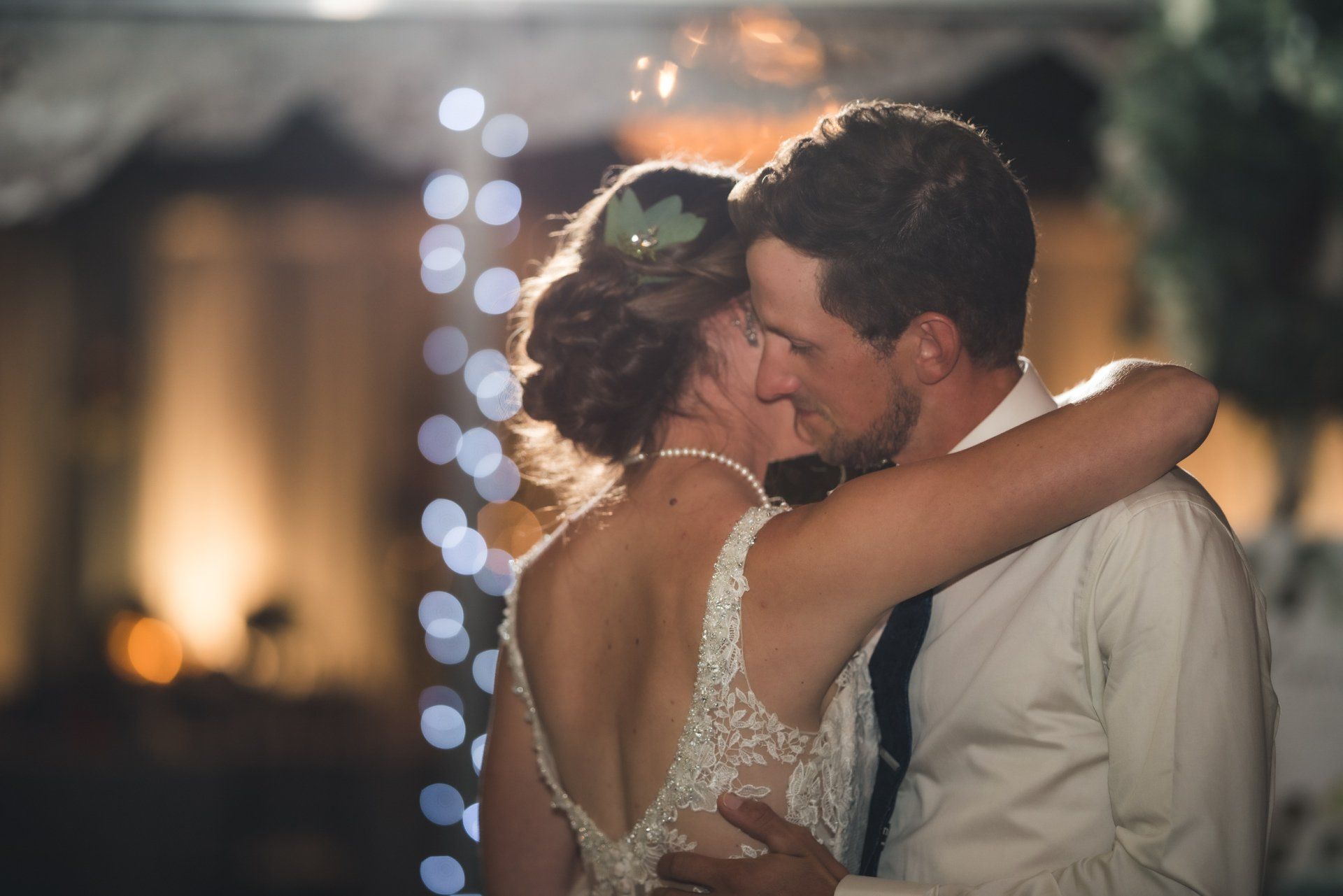 A bride and groom are kissing during their first dance at their wedding reception.