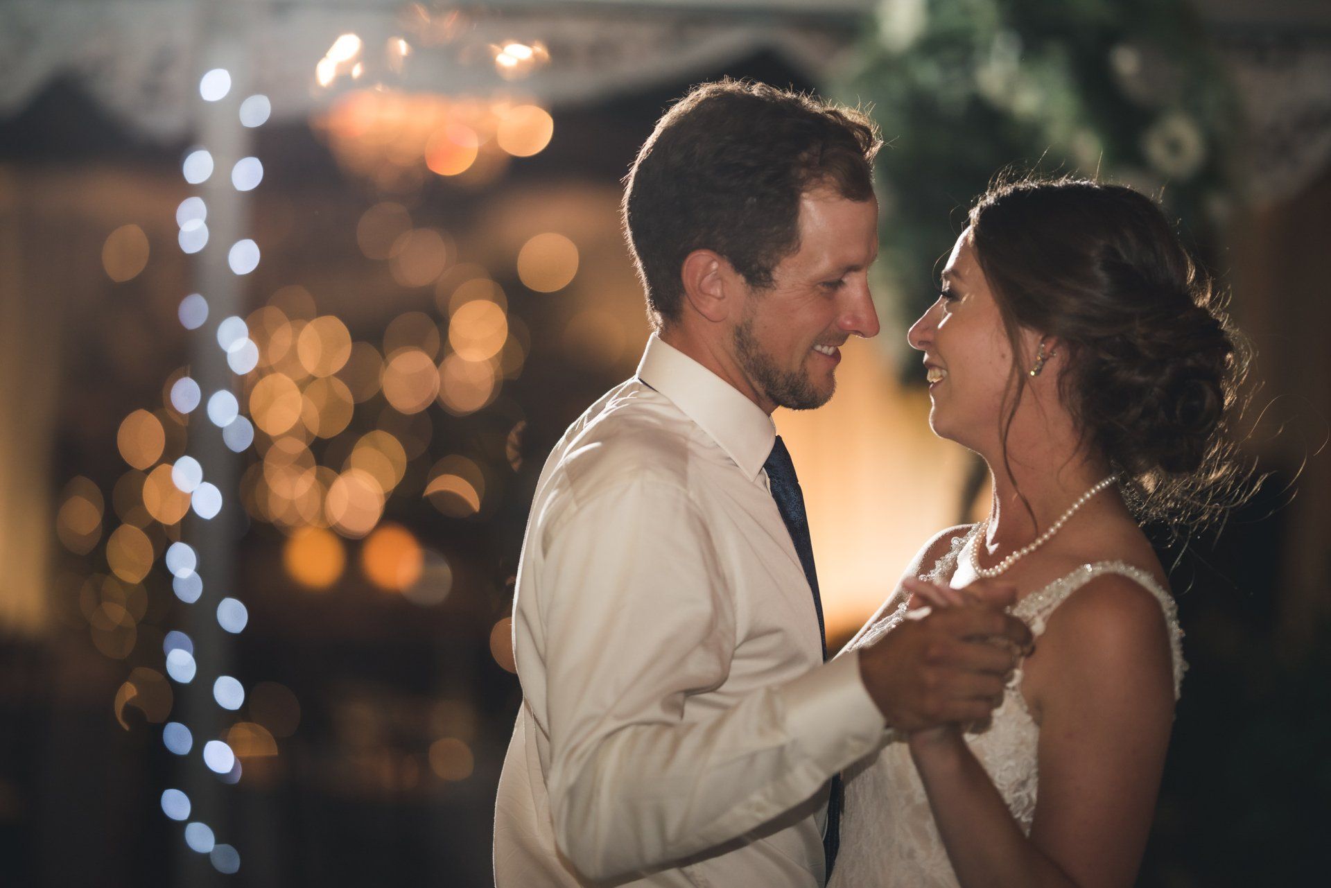 A bride and groom are dancing together at their wedding reception.