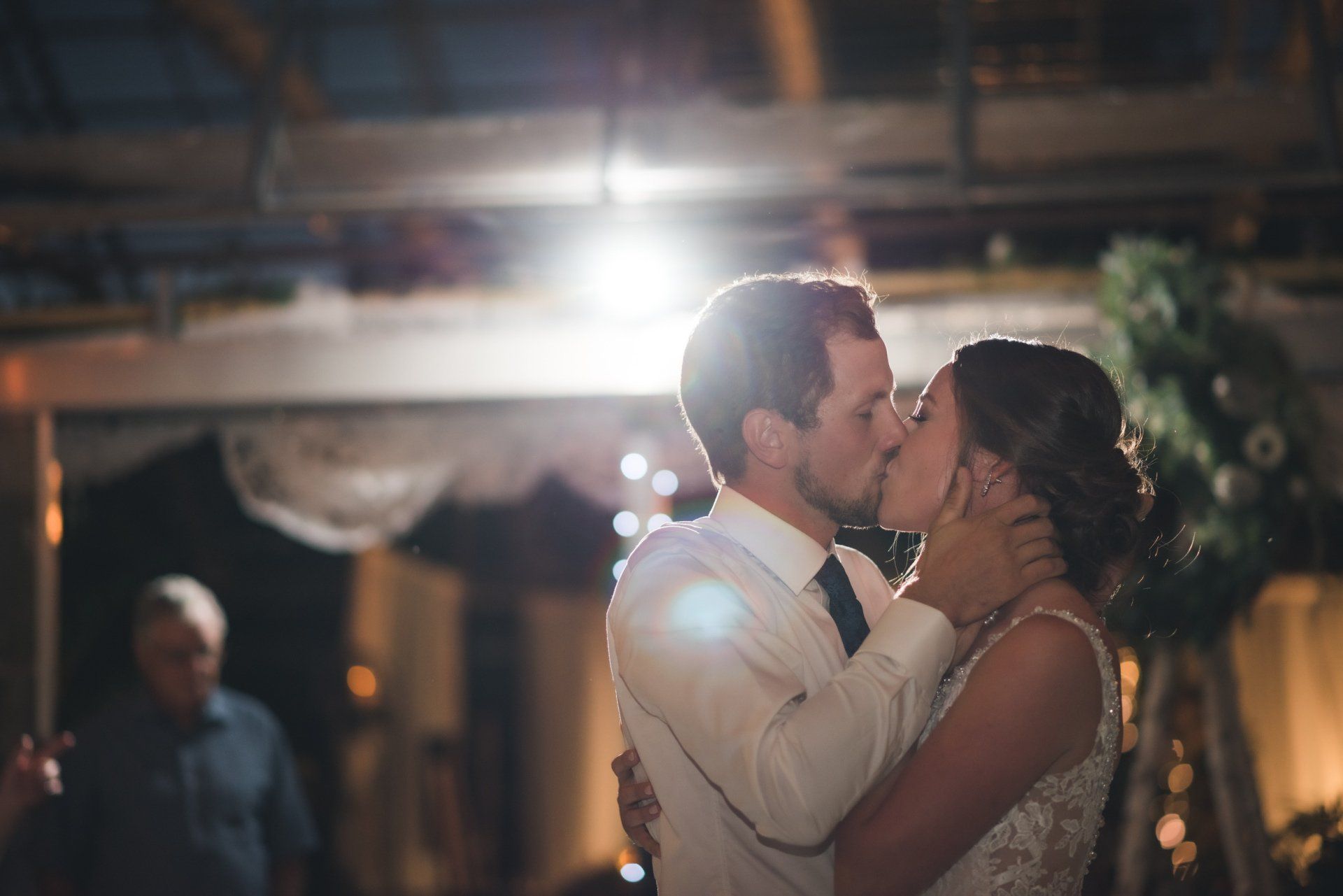 A bride and groom are kissing during their first dance at their wedding reception.