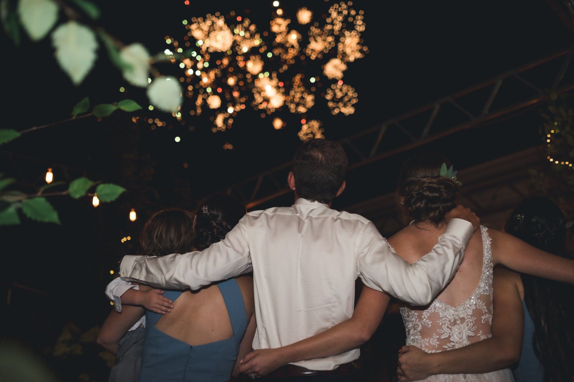 A group of people are watching fireworks at a wedding reception.