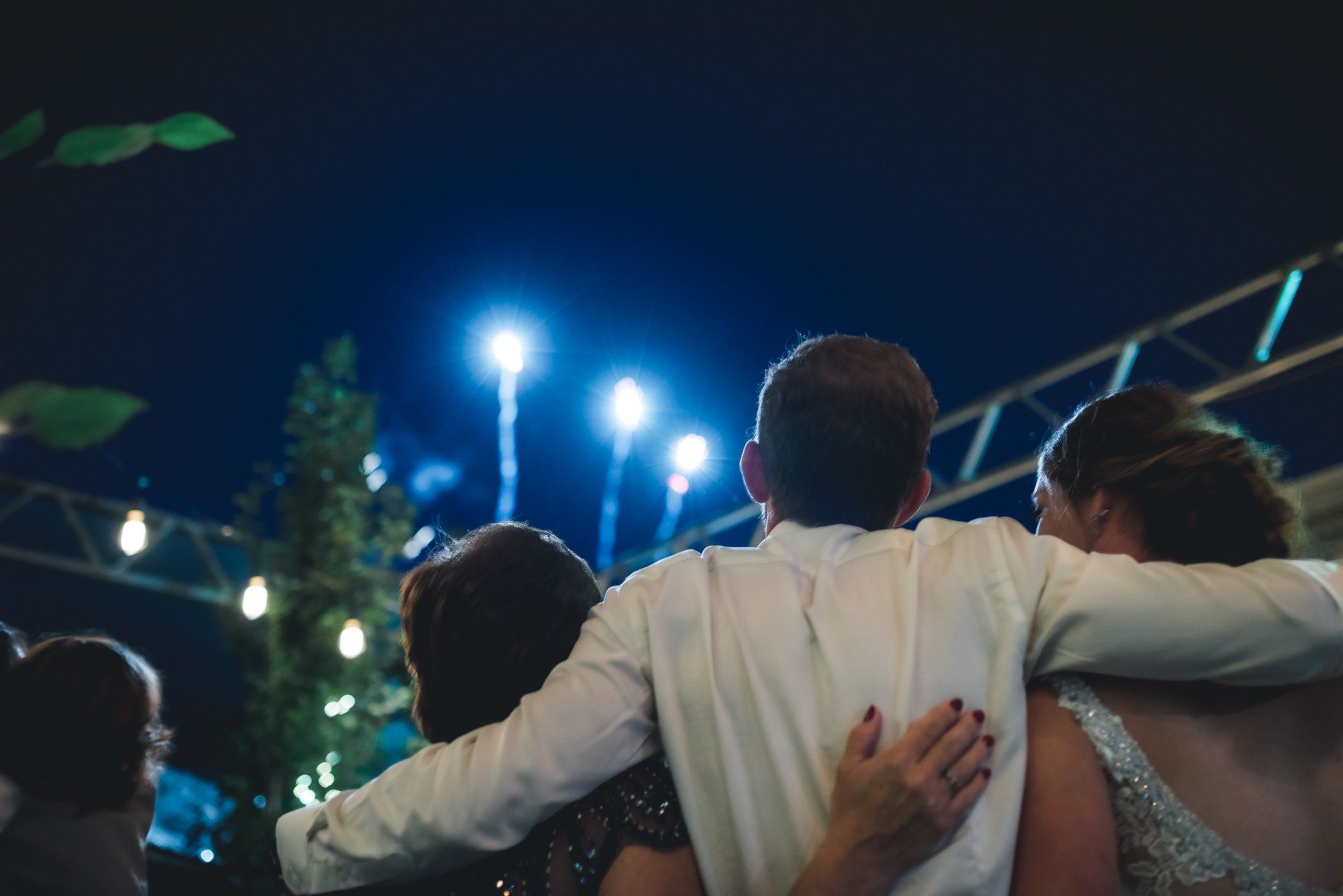 A group of people are hugging each other at a wedding reception.