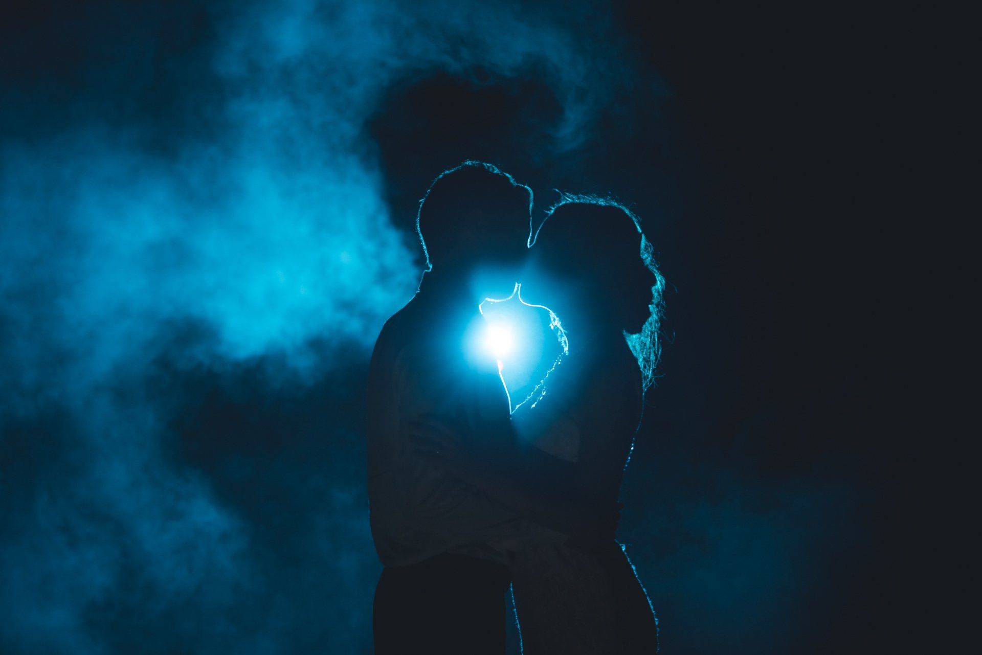 A silhouette of a man and woman kissing in the dark.