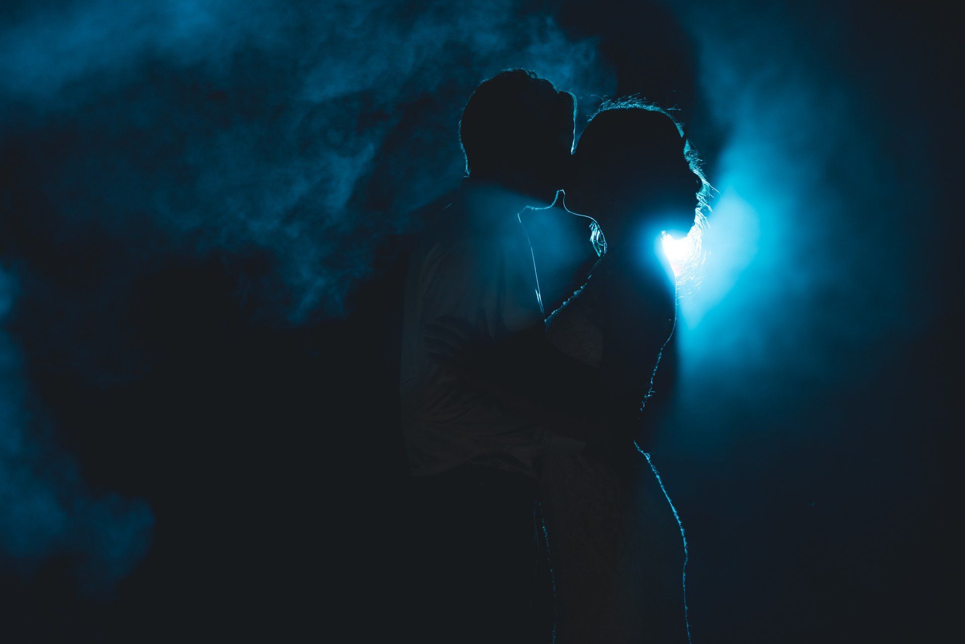 A silhouette of a bride and groom kissing in the dark.
