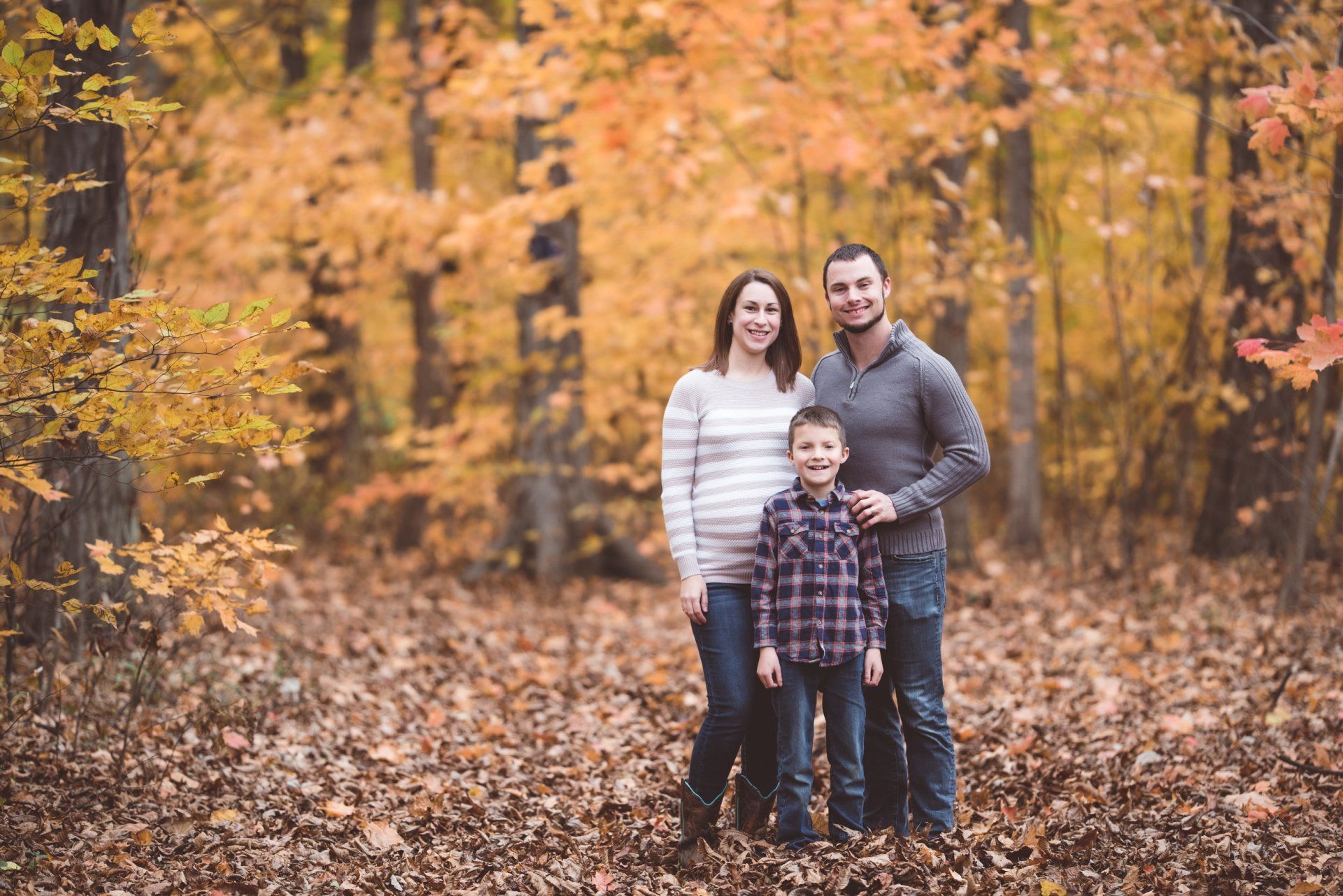 A family is posing for a picture in the woods.