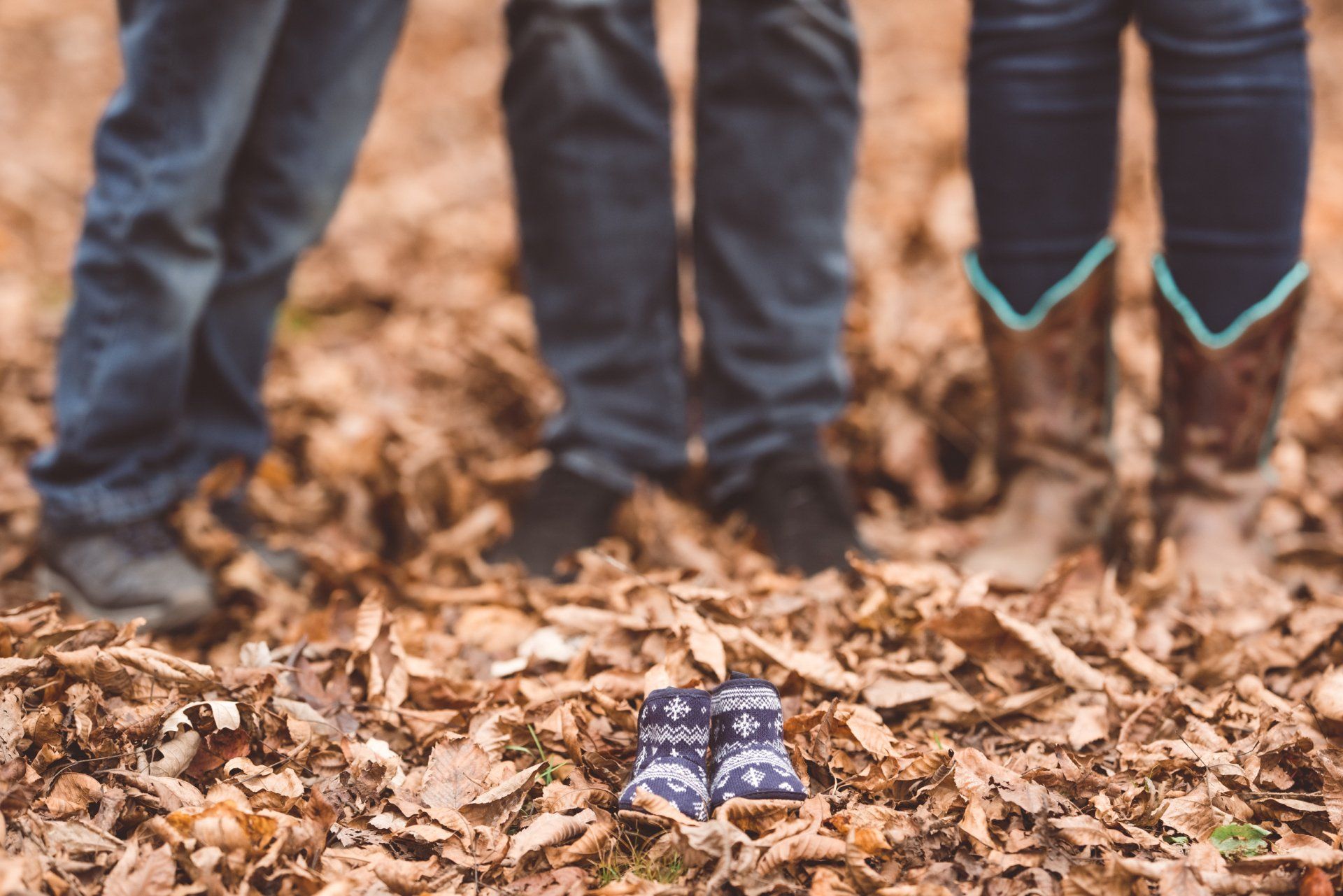 A couple of people standing next to each other in a pile of leaves.
