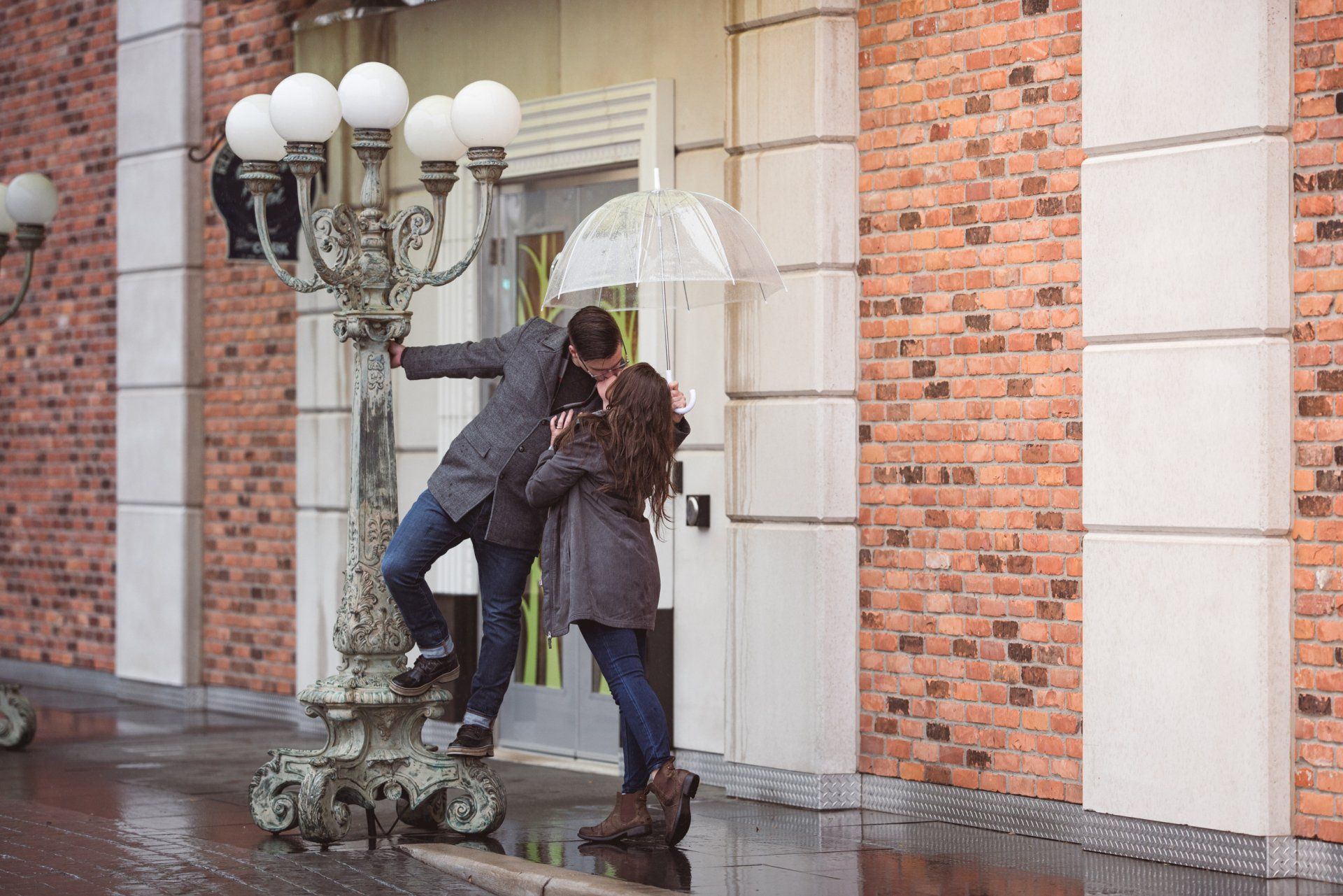 A man and a woman are kissing under an umbrella in the rain.