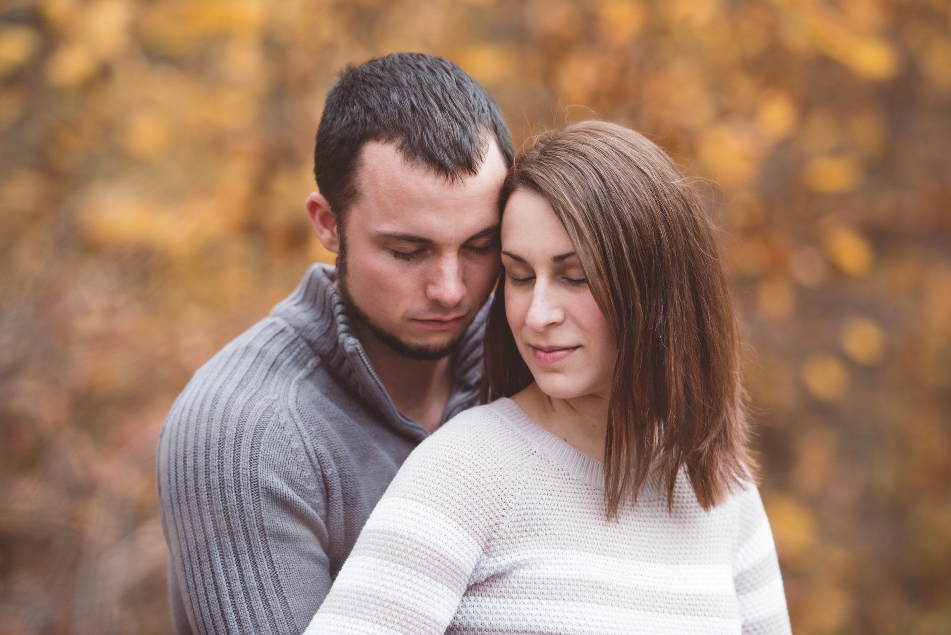 A man and a woman are hugging each other in the woods.