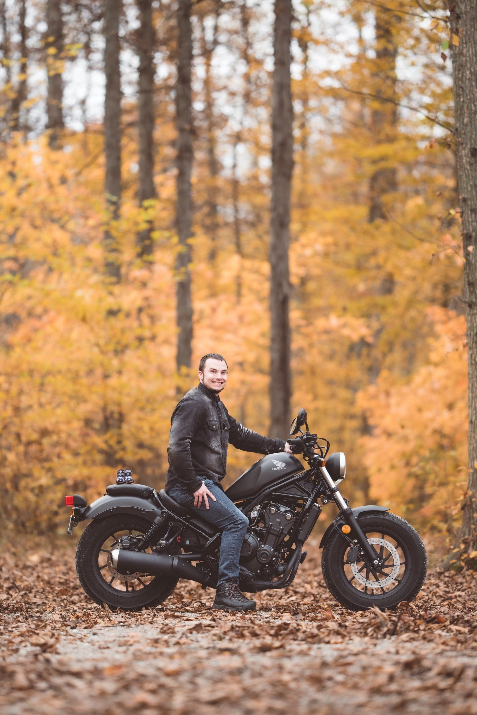 A man is sitting on a motorcycle in the woods.