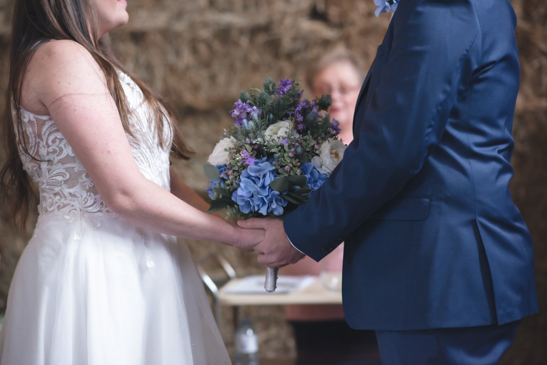 A bride and groom are holding hands during their wedding ceremony.