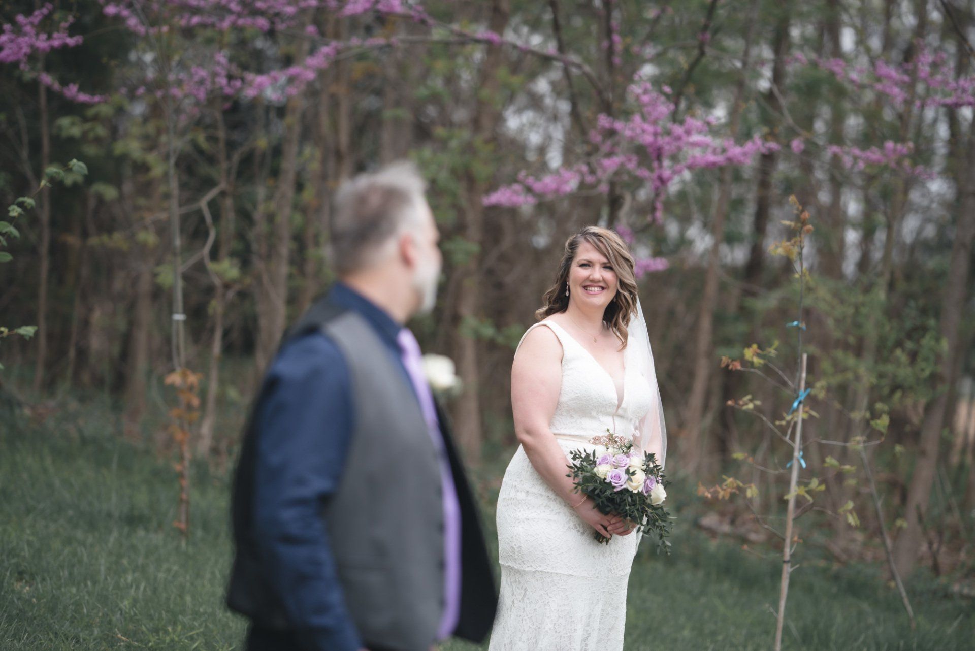 A bride and groom are posing for a picture in the woods.