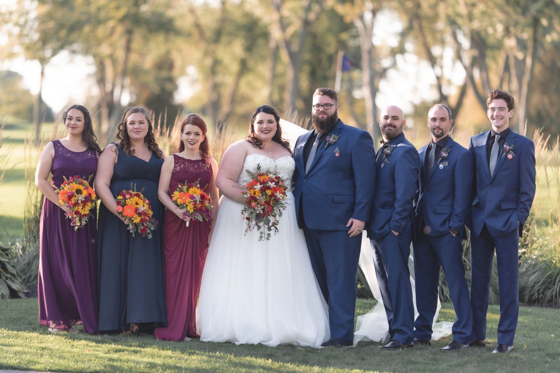 A bride and groom are posing for a picture with their wedding party.