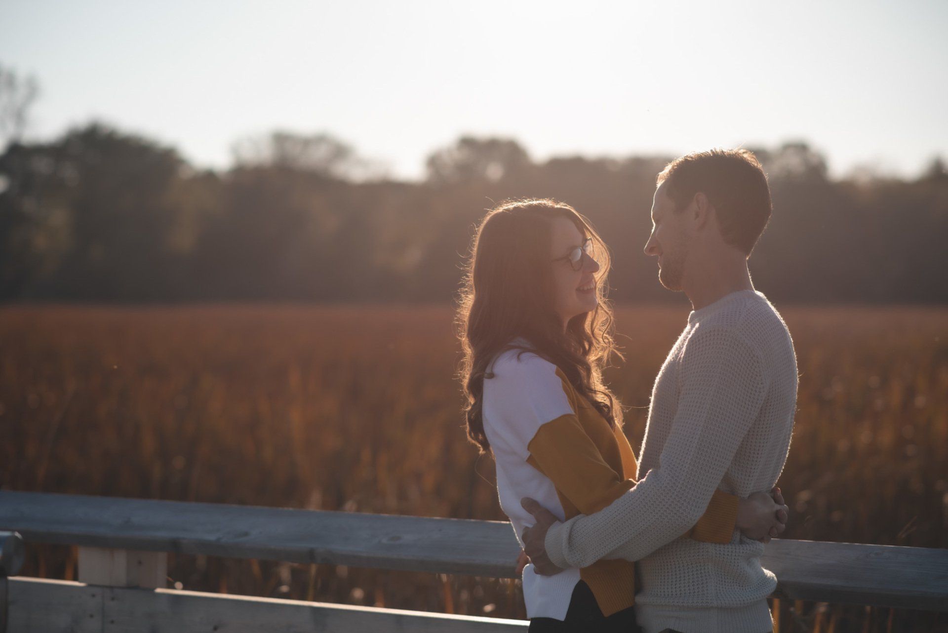 A man and a woman are hugging and looking at each other in a field.