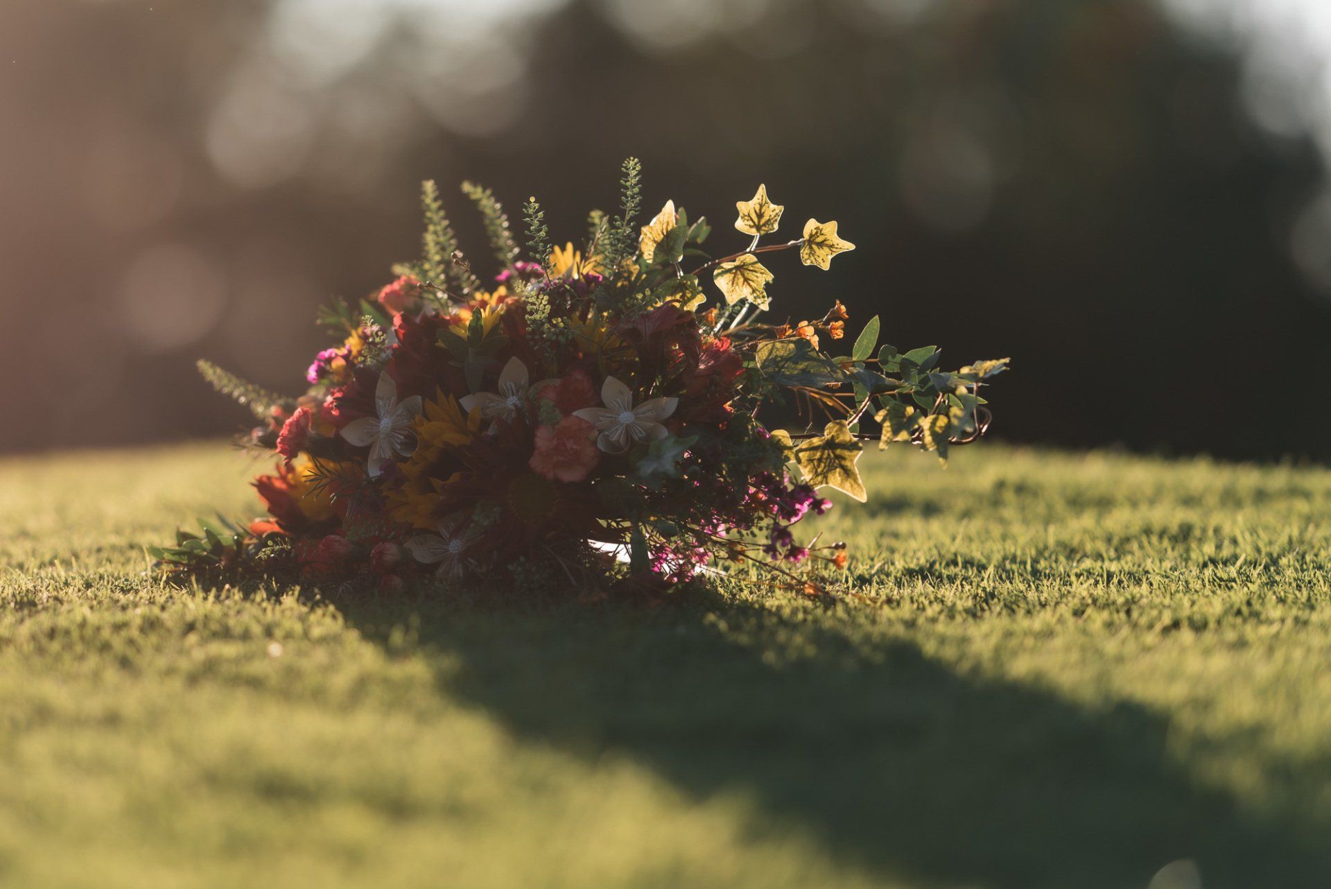 A bouquet of flowers is laying on the grass in a field.